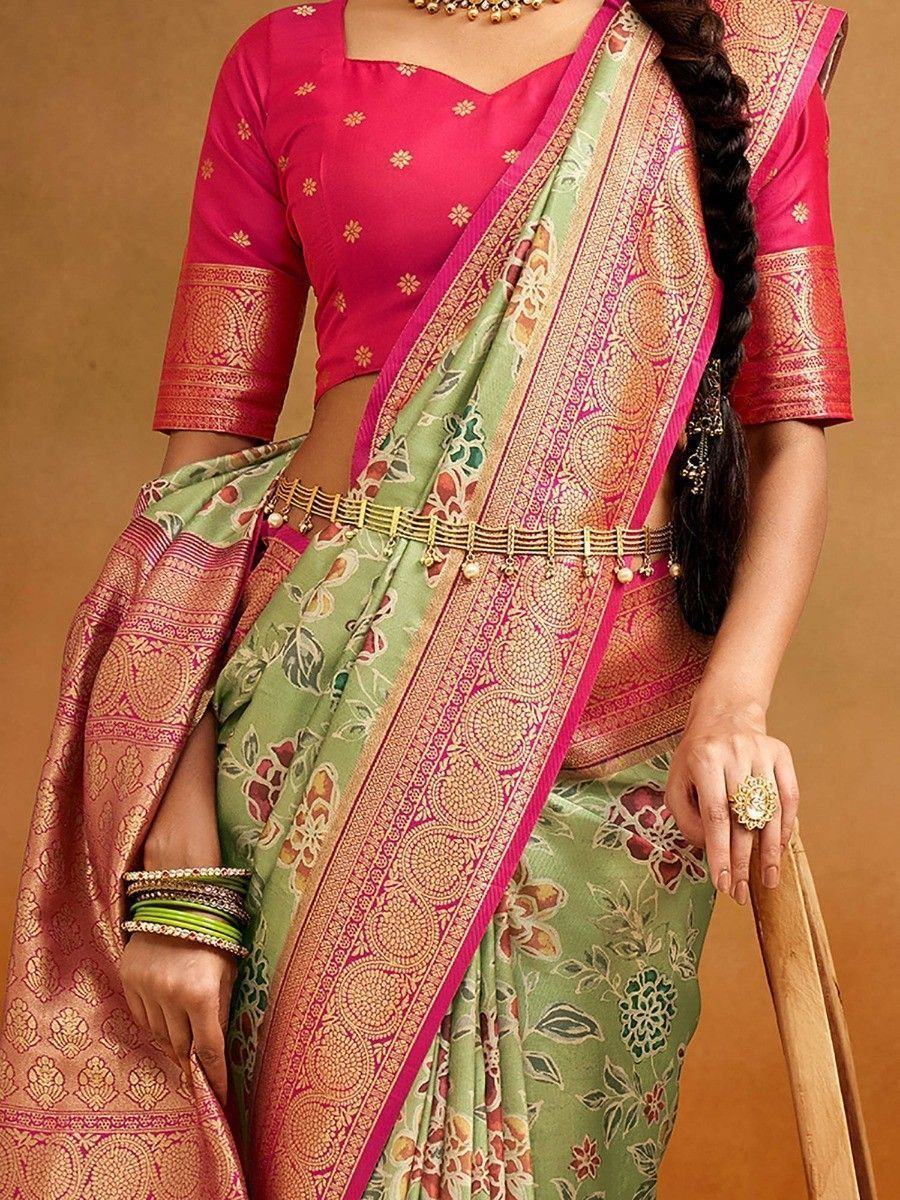 Green floral saree with pink border and gold embroidery, paired with matching blouse and traditional jewelry