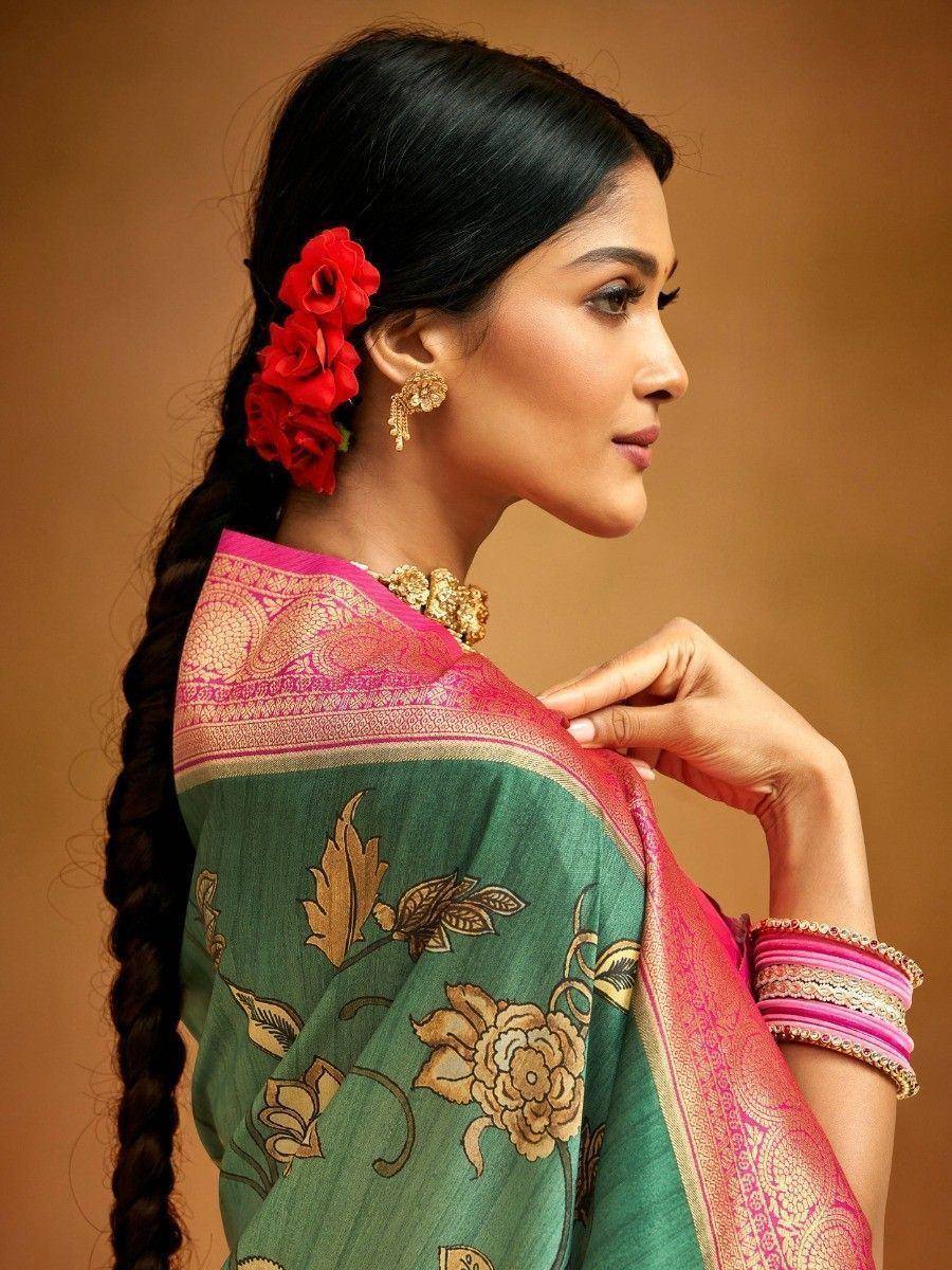 Woman in green floral saree with pink border, gold jewelry, and red flower braid