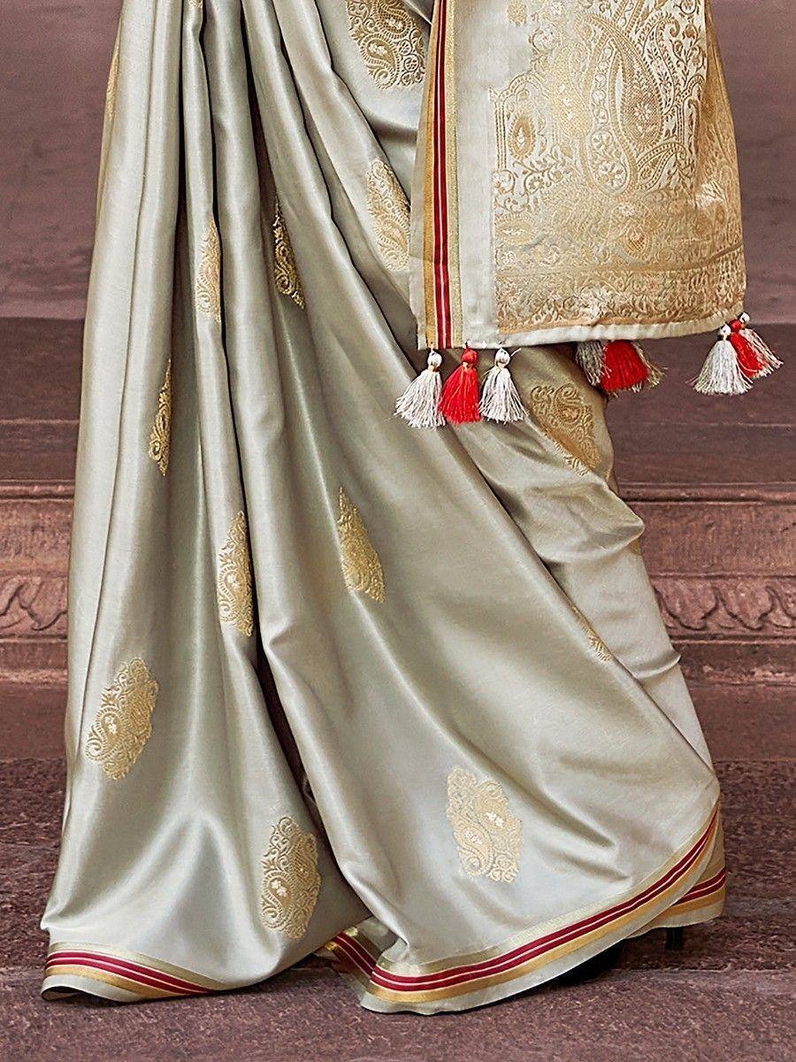 Elegant beige saree with gold paisley embroidery and red-white tassels, perfect for Indian ethnic wear occasions.