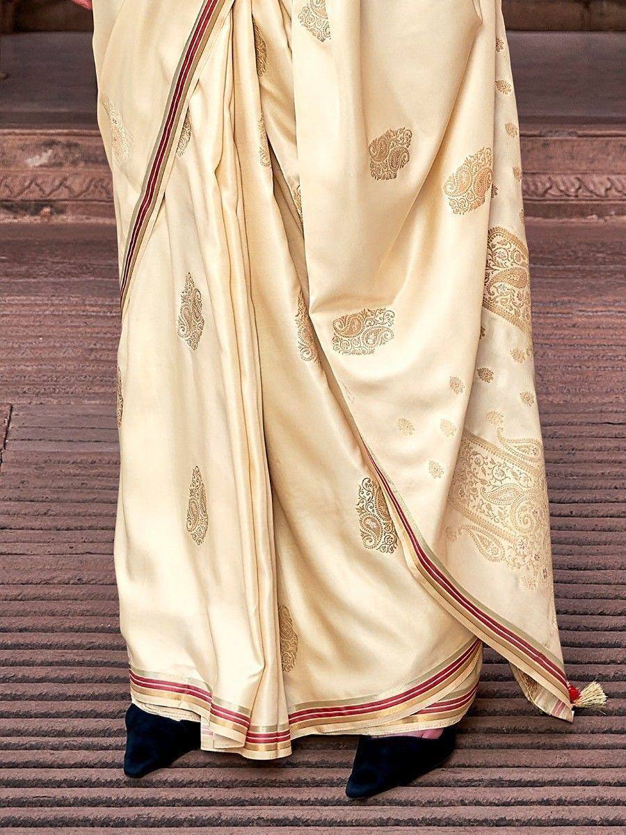 Cream silk saree with gold paisley print and red border, elegant Indian ethnic wear