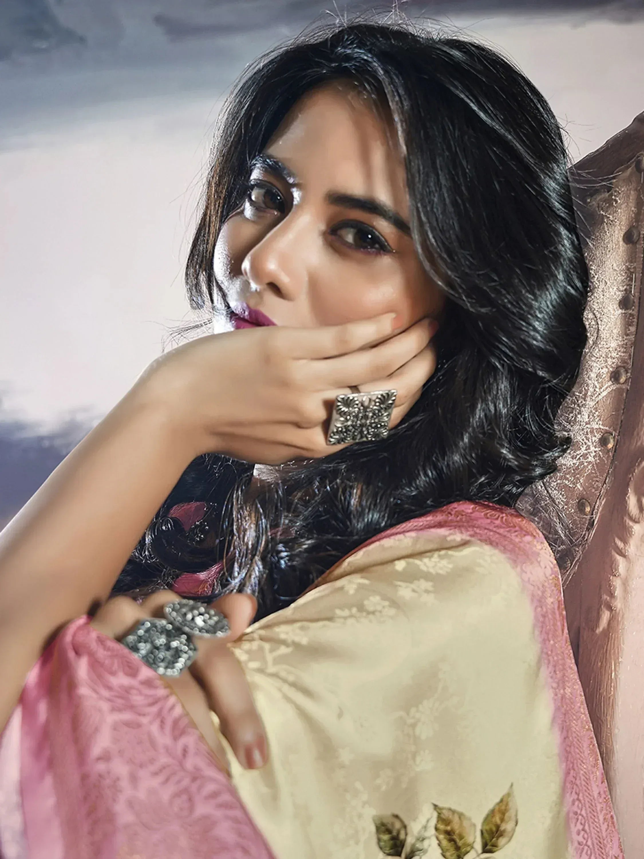 Woman in elegant ethnic saree with floral embroidery and statement rings, showcasing Indian designer wear.