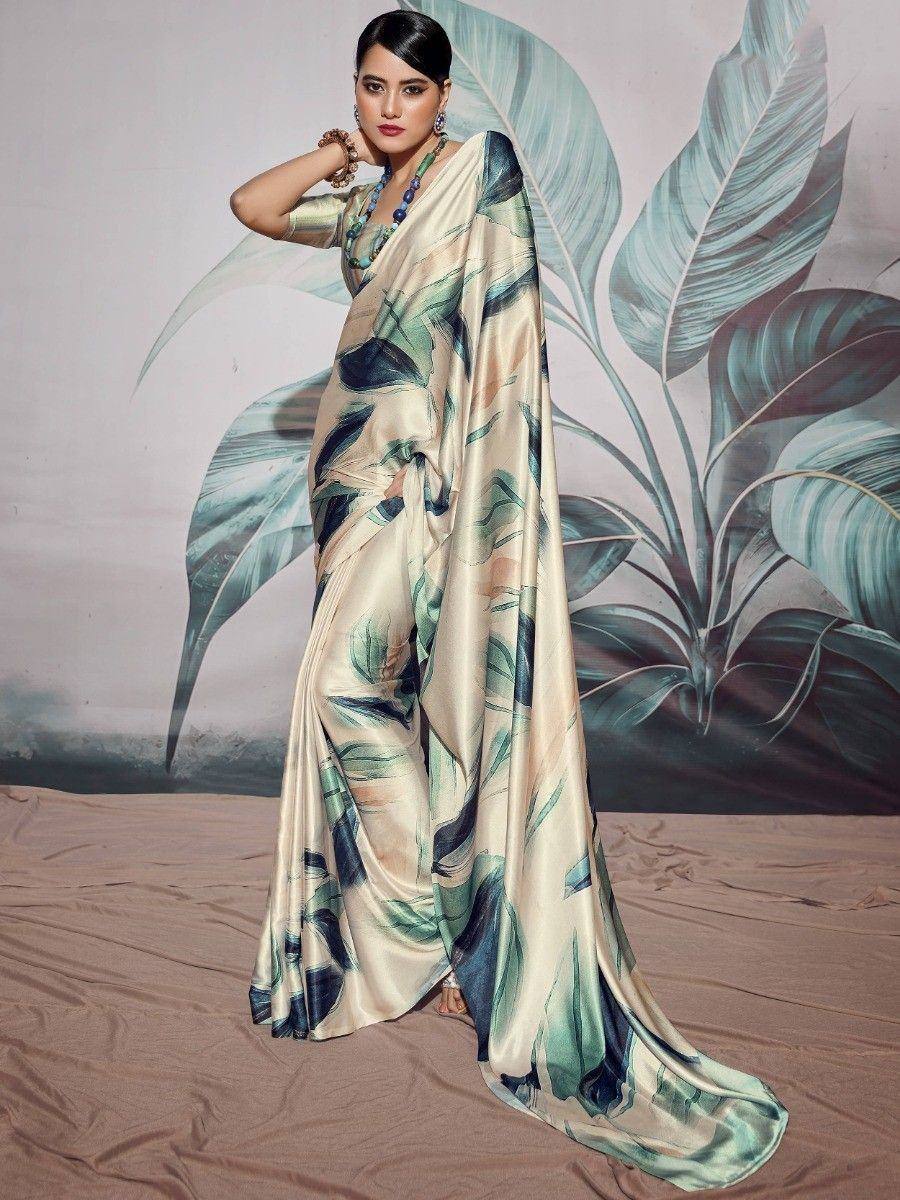 Woman in elegant cream saree with green leaf print, styled with statement jewelry for ethnic occasions.