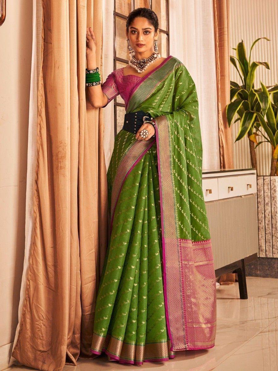 Green and pink ethnic saree with gold motifs, paired with designer blouse and statement jewelry