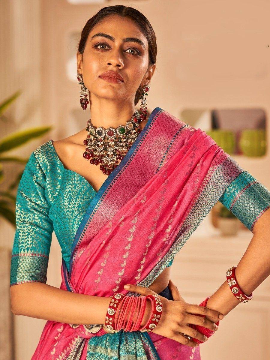 Woman in vibrant pink and teal designer saree with intricate embroidery, styled with traditional jewelry for ethnic occasions