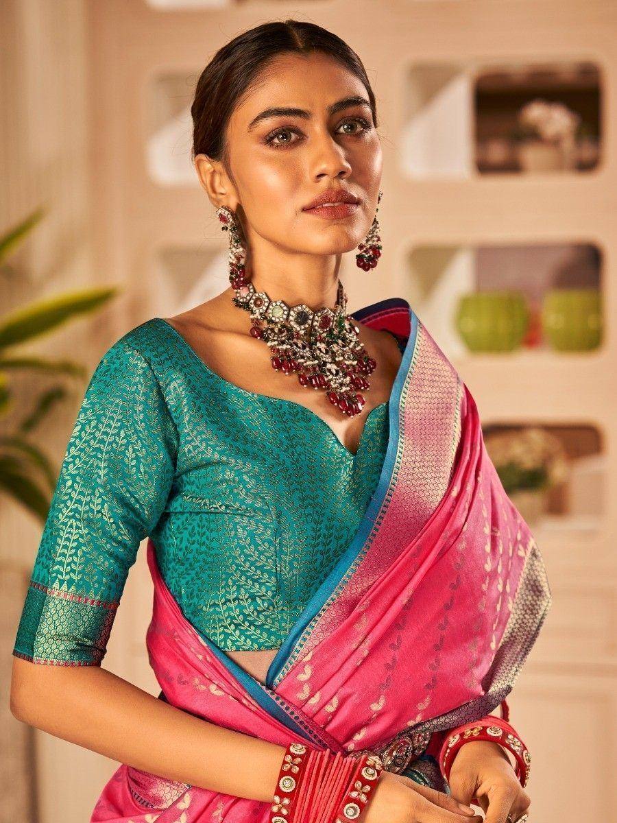 Woman in teal embroidered blouse and pink saree with statement jewelry, ethnic Indian wear