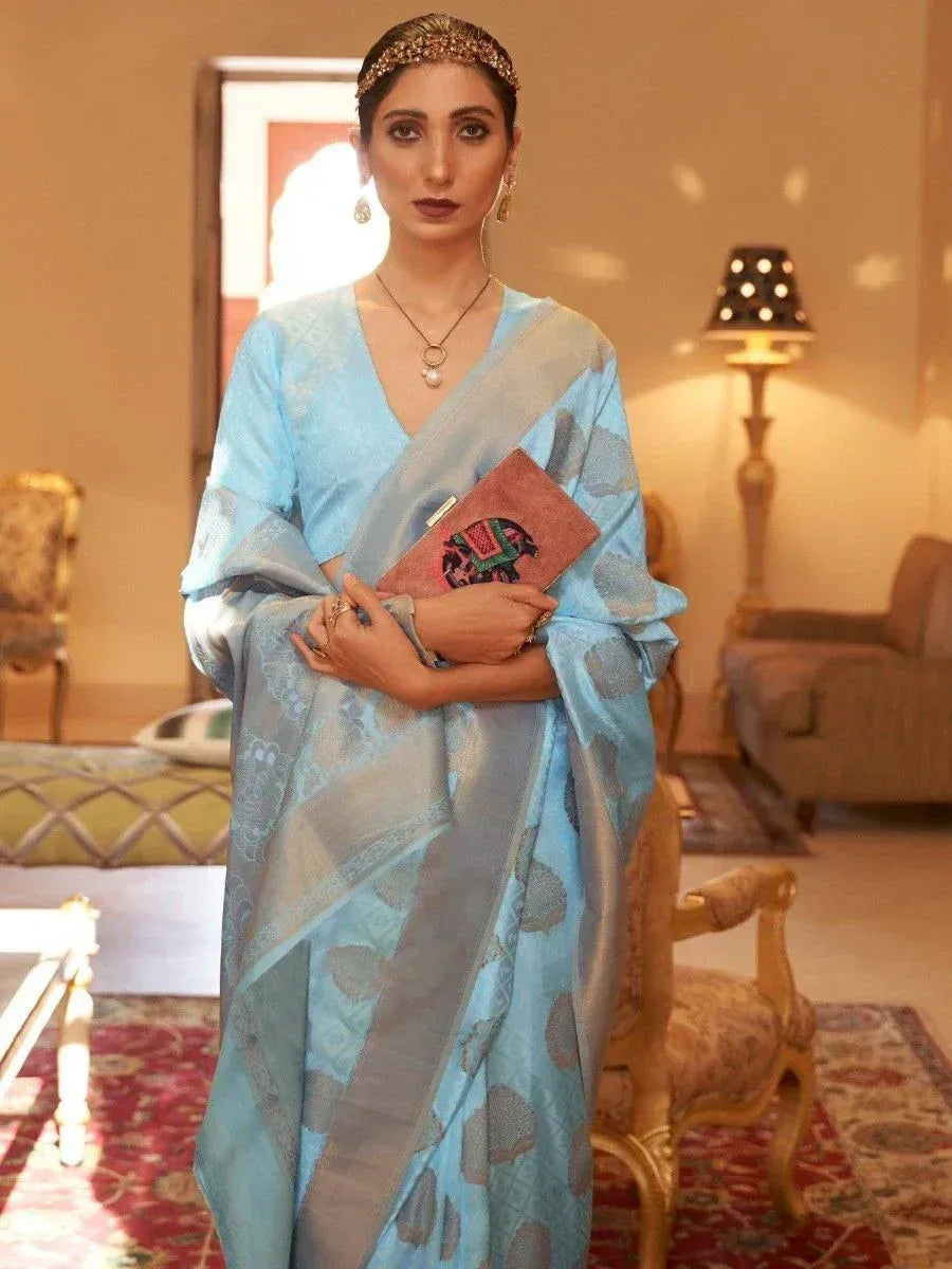 Elegant light blue saree with silver motifs, paired with statement jewelry and clutch, perfect for Indian ethnic occasions.