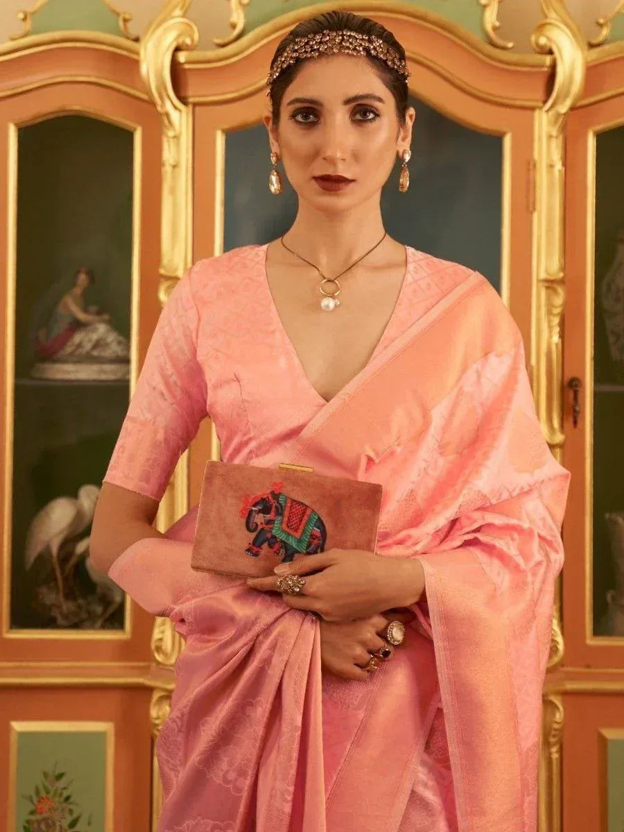 Woman in pink designer saree with elephant clutch, ethnic jewelry, and ornate background