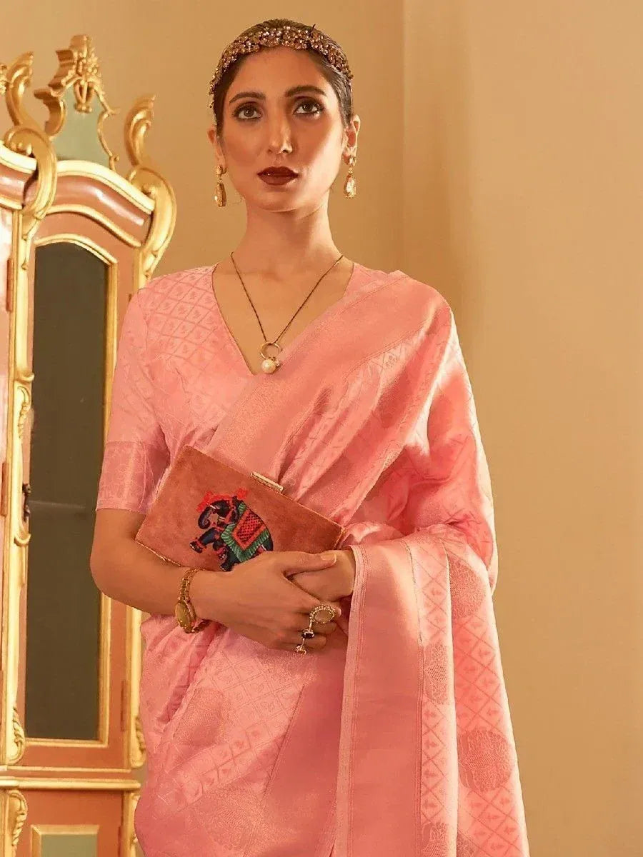 Pink designer saree with embroidered blouse, ethnic jewelry, and elephant clutch for Indian occasions