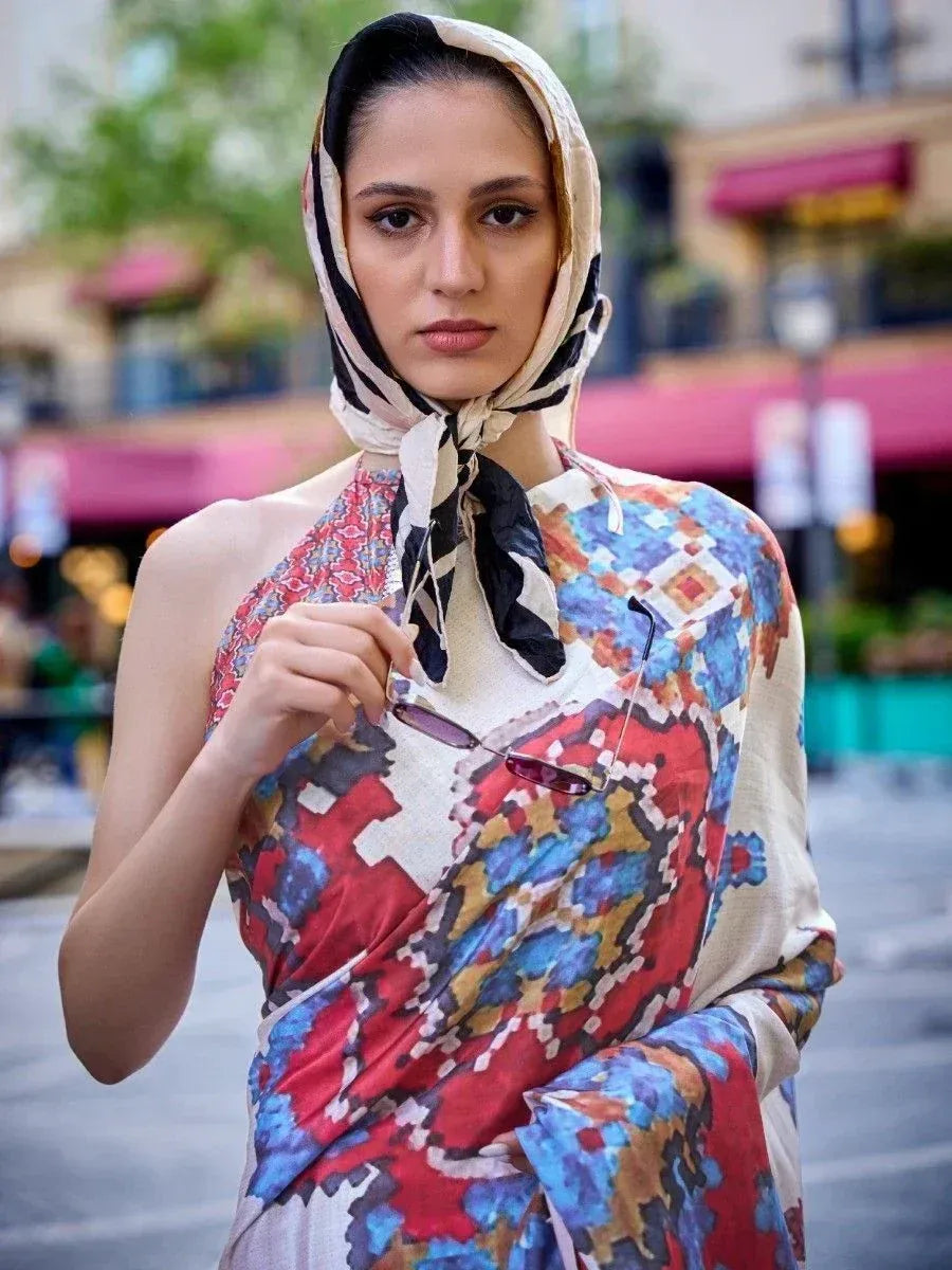Woman in colorful printed ethnic gown with matching headscarf, holding sunglasses outdoors