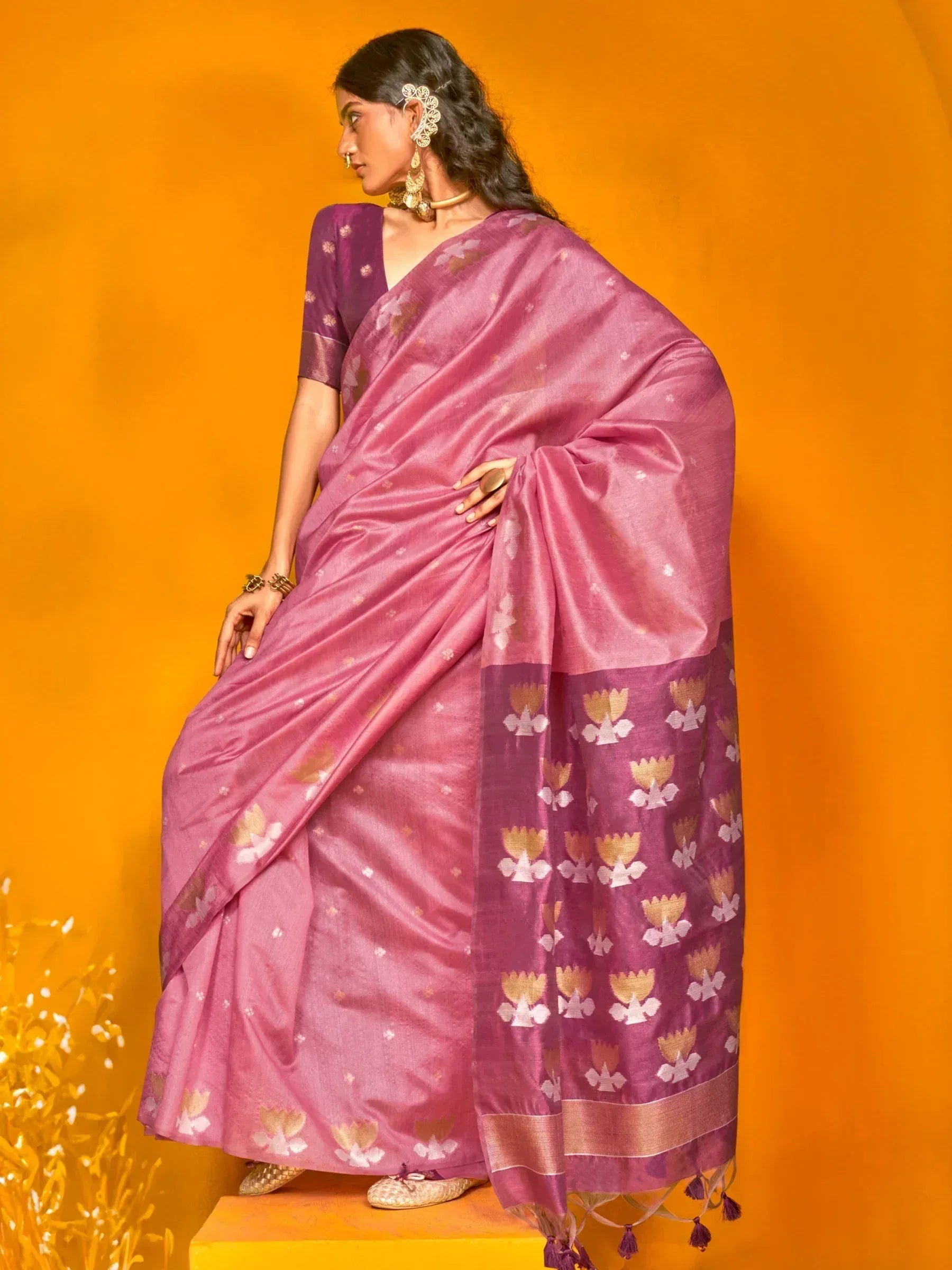 Purple floral print saree with gold accents, styled with traditional jewelry against orange backdrop