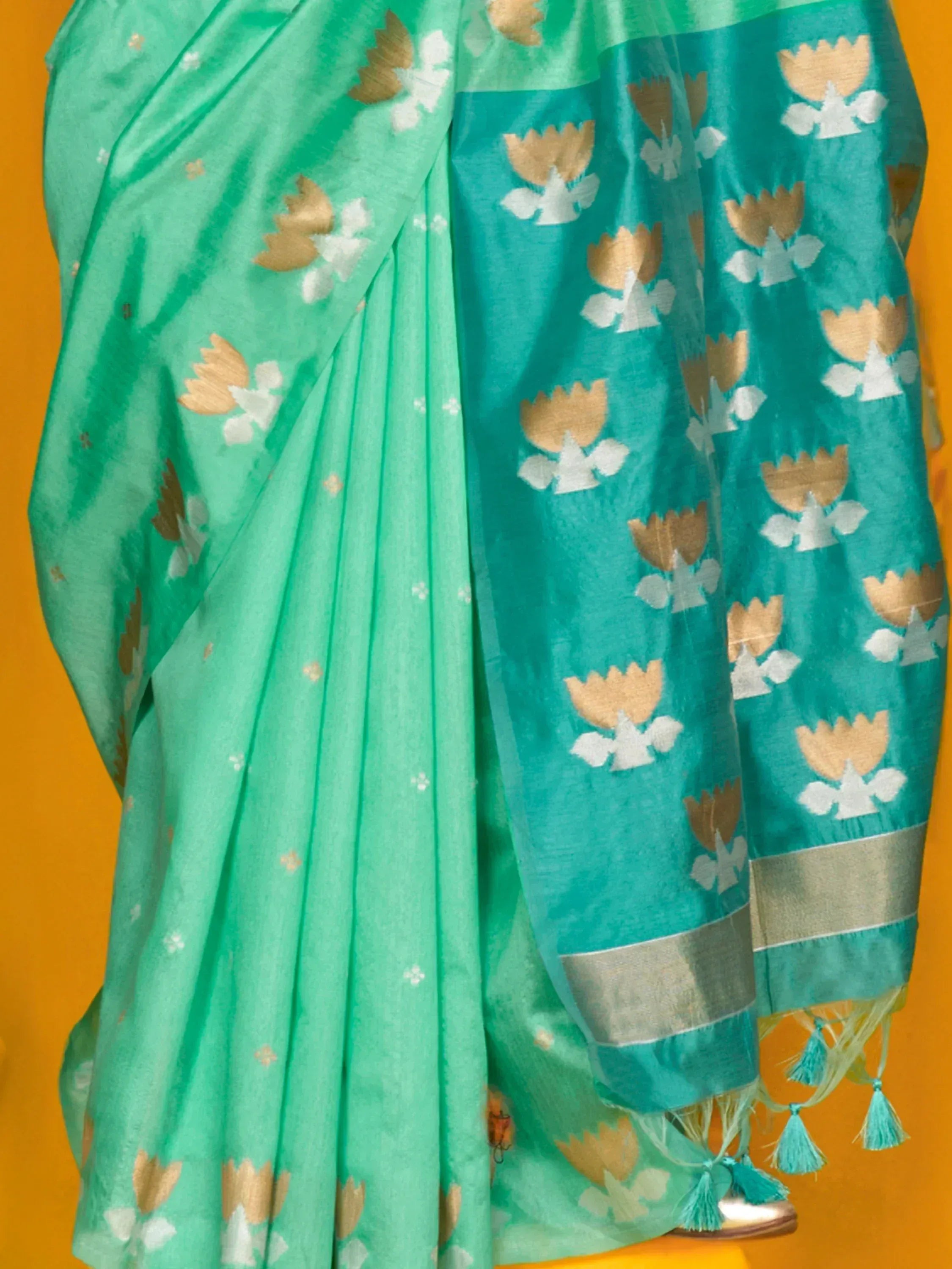 Teal and mint green saree with gold and white floral motifs, tassels, and woven border for ethnic wear