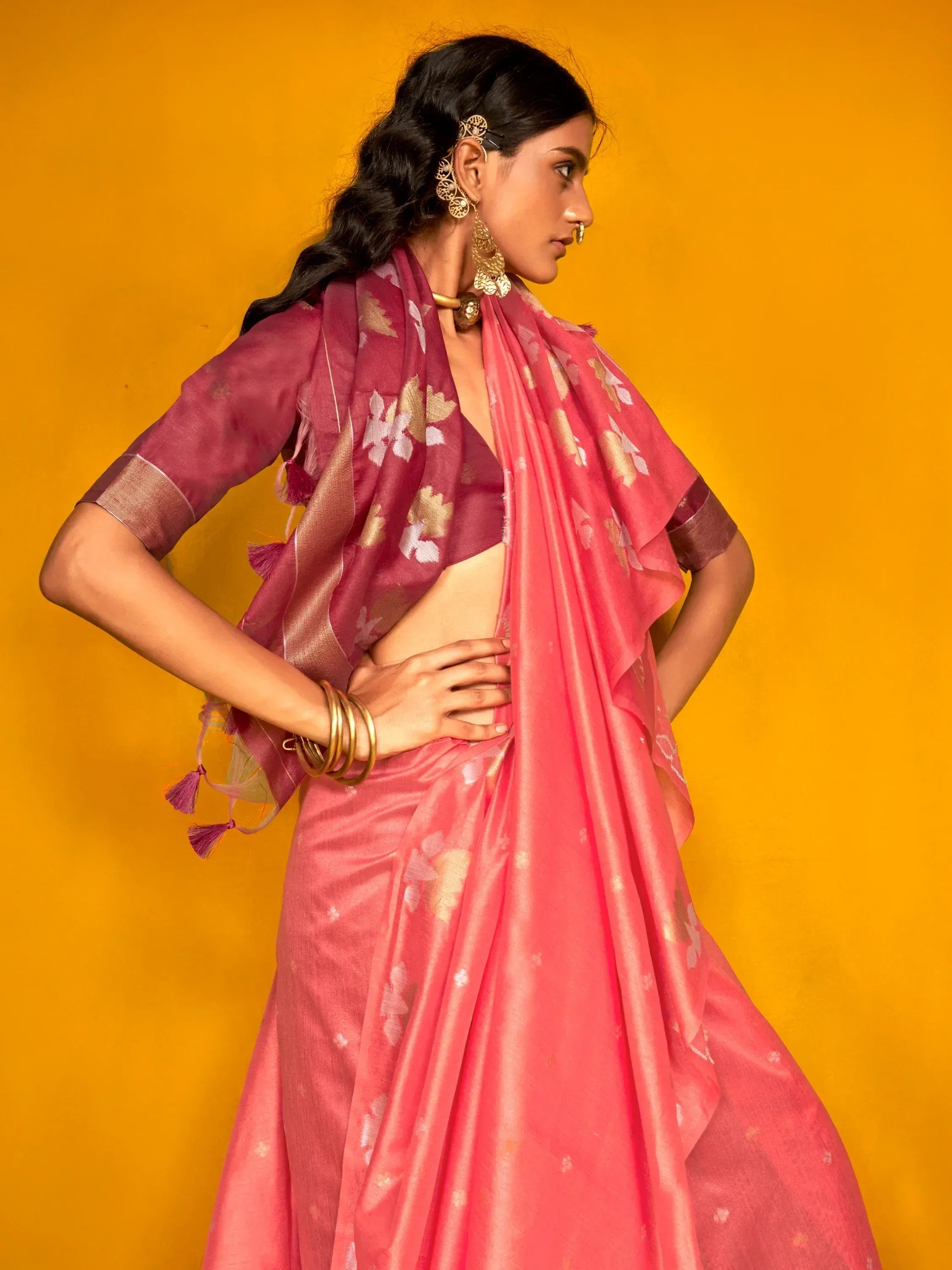Pink floral lehenga choli with gold embroidery, styled with traditional jewelry against yellow backdrop