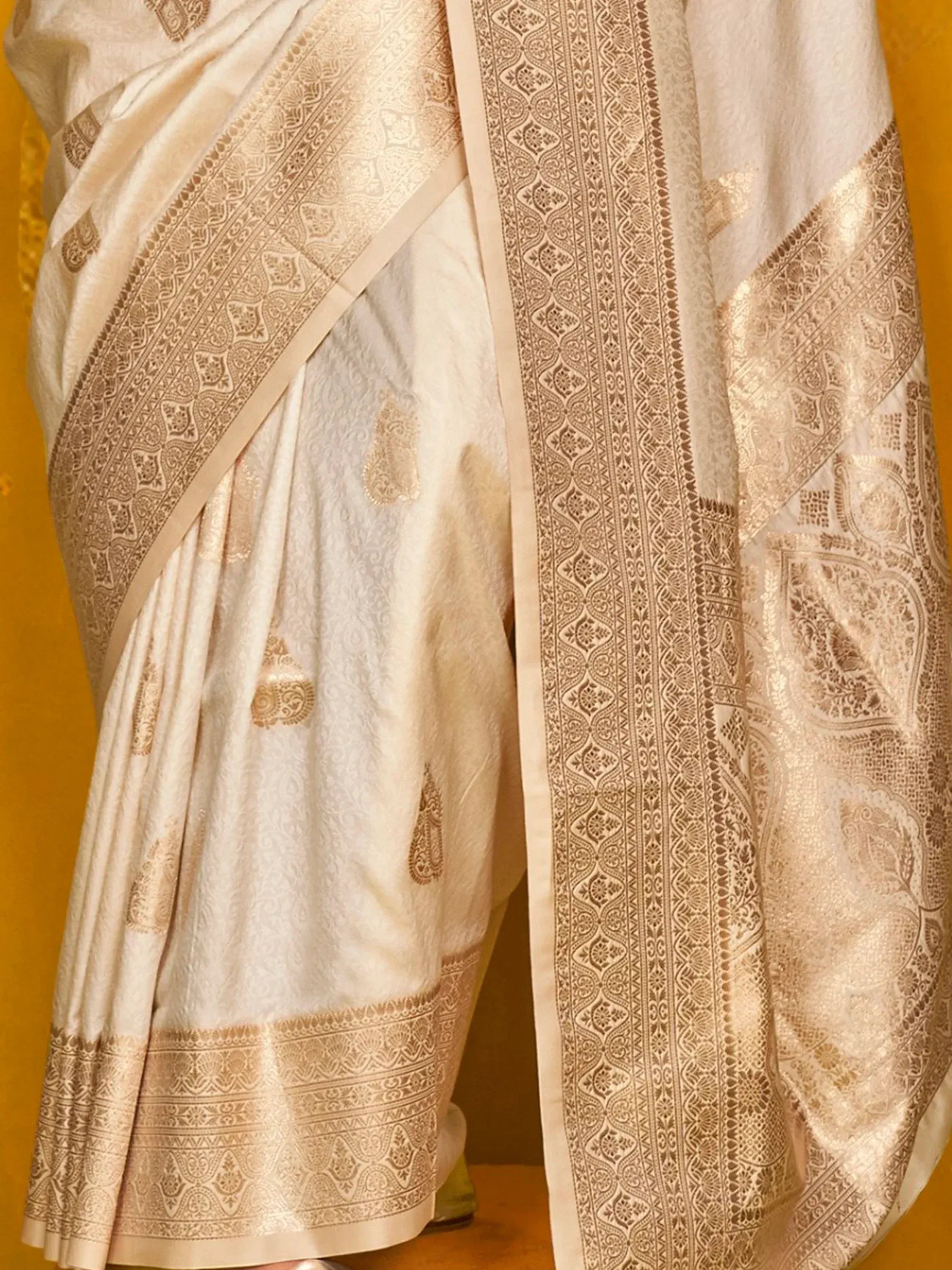 Cream and gold embroidered saree with intricate paisley and border designs, ideal for ethnic wear occasions.