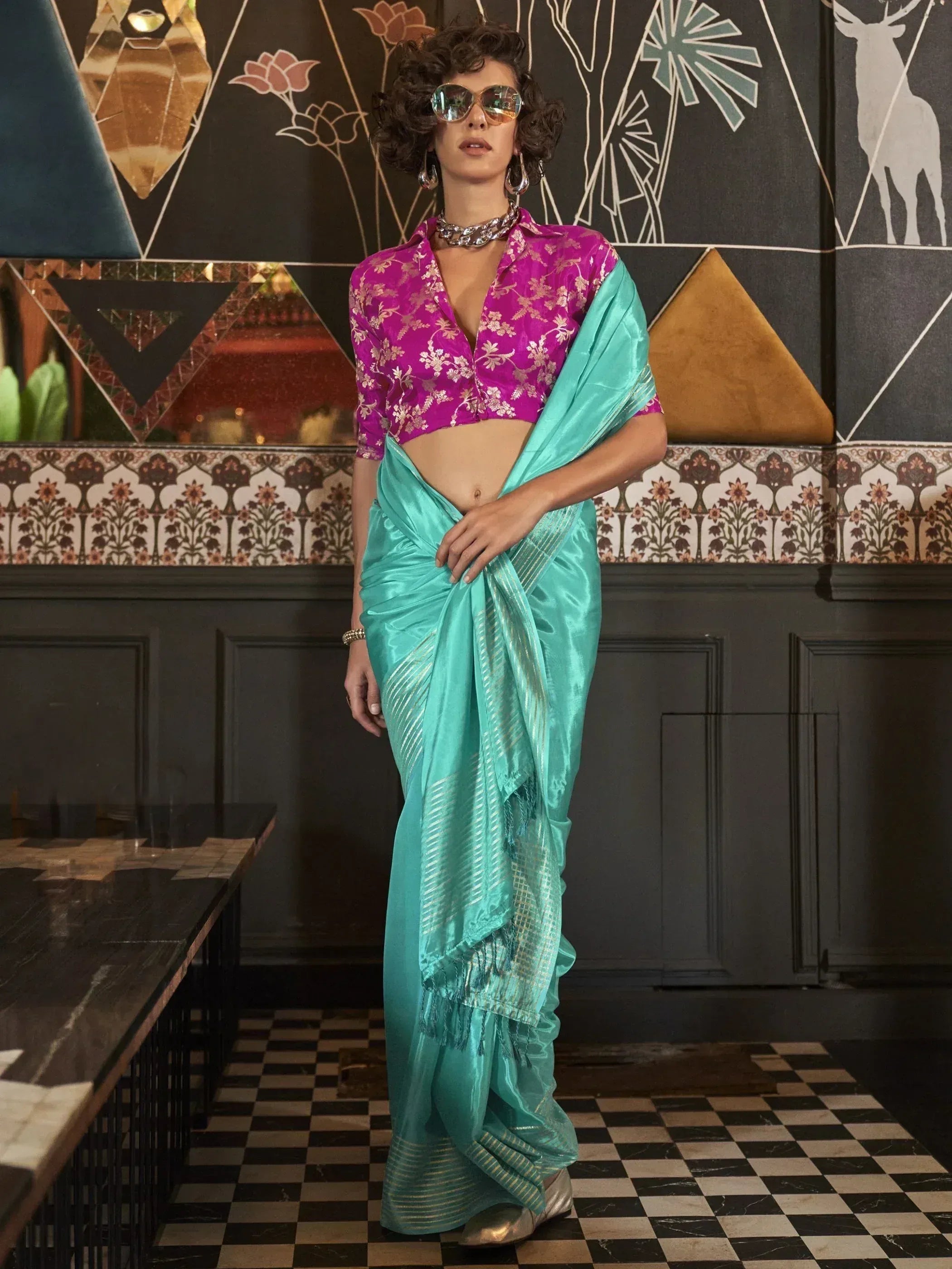 Turquoise saree with gold stripes paired with a pink floral blouse, styled for ethnic wear.