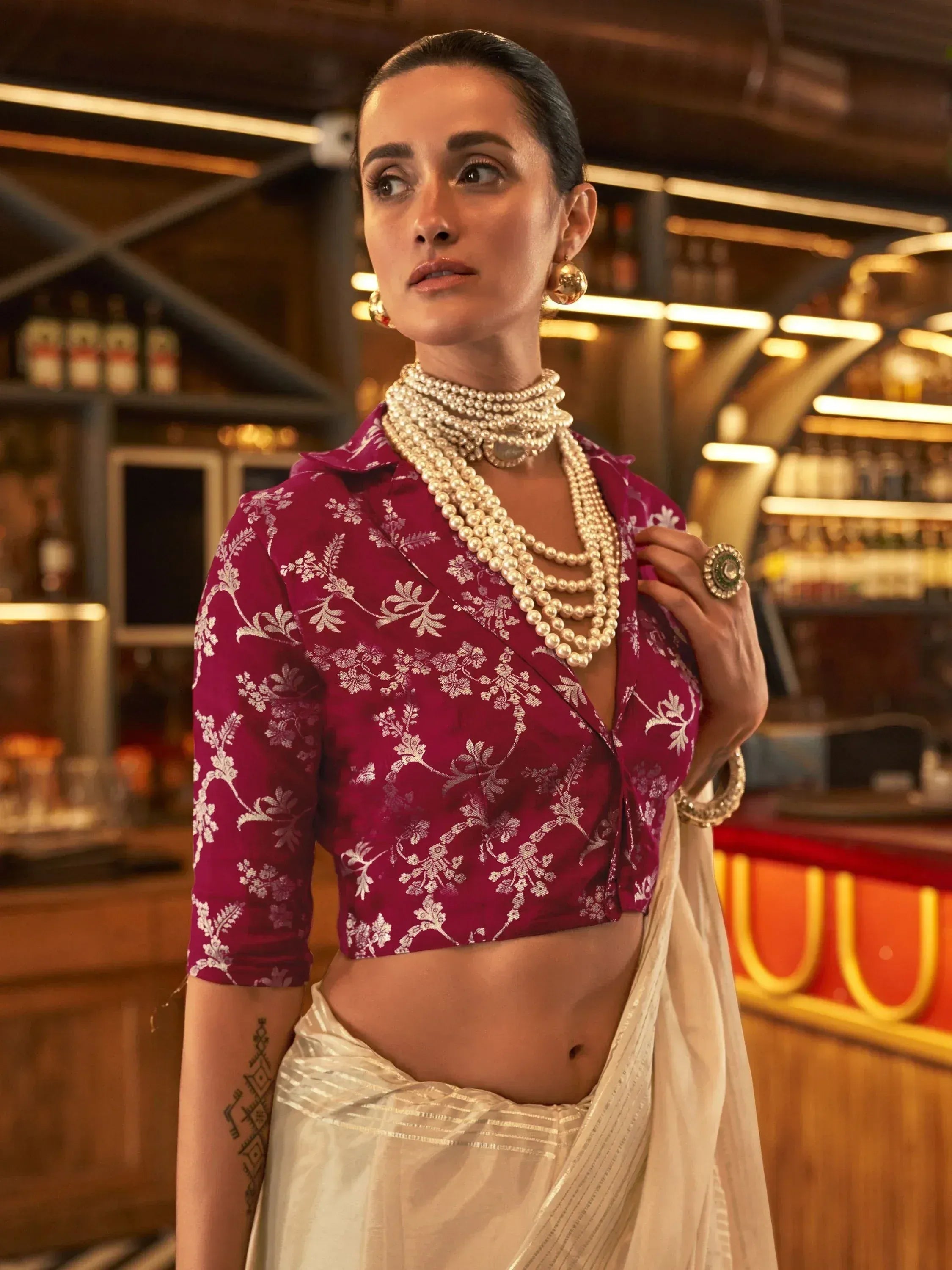 Woman in maroon floral blouse and cream saree with pearl necklace, elegant Indian ethnic wear