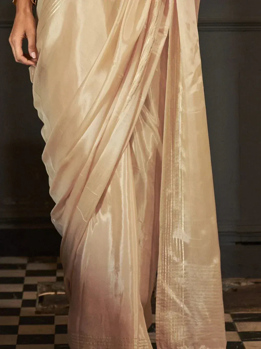 Elegant beige saree with shimmering texture and subtle pleats, perfect for ethnic occasions.