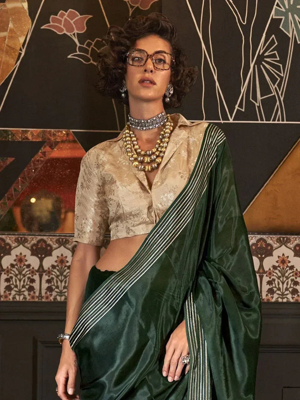 Elegant green silk saree with gold stripes paired with floral blouse, perfect for Indian ethnic wear occasions.