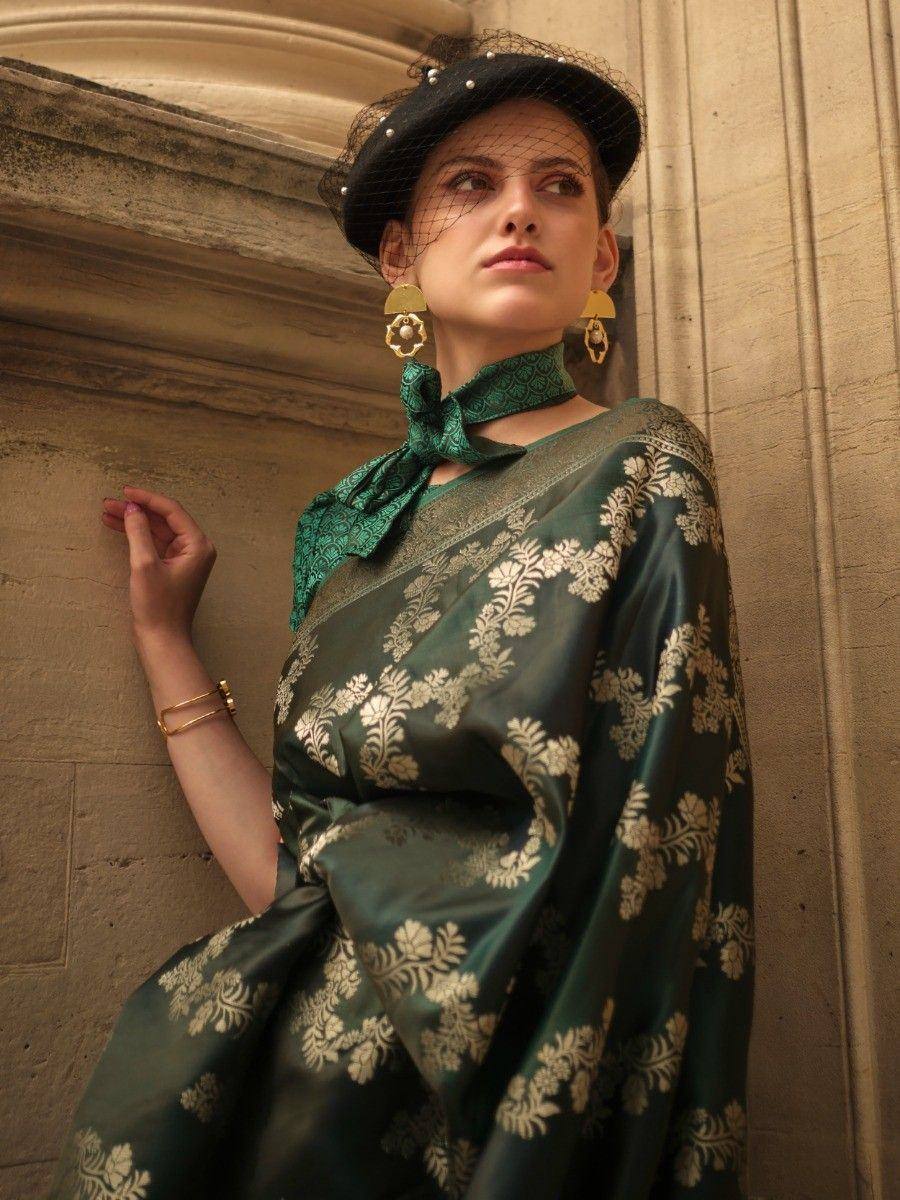 Elegant green saree with gold floral print, styled with black hat and statement earrings for ethnic wear.