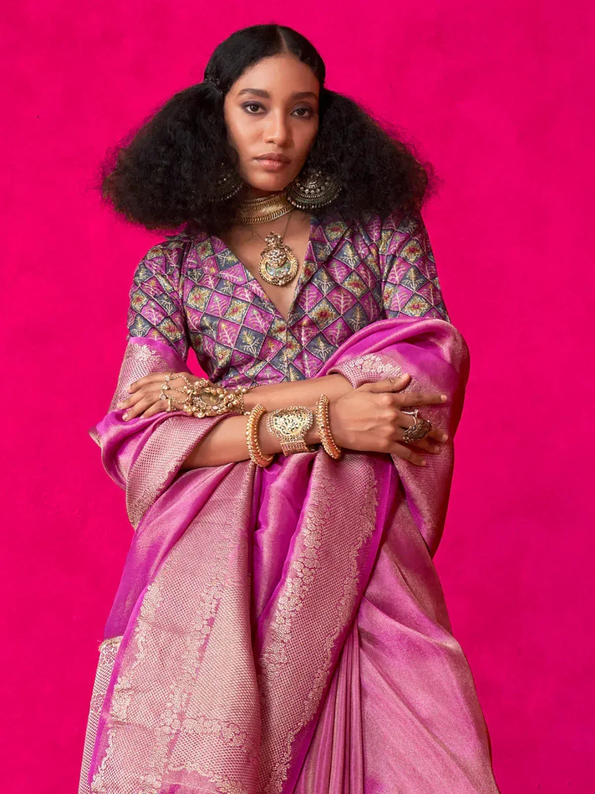 Woman in vibrant pink designer saree with gold embroidery and traditional jewelry, perfect for ethnic occasions