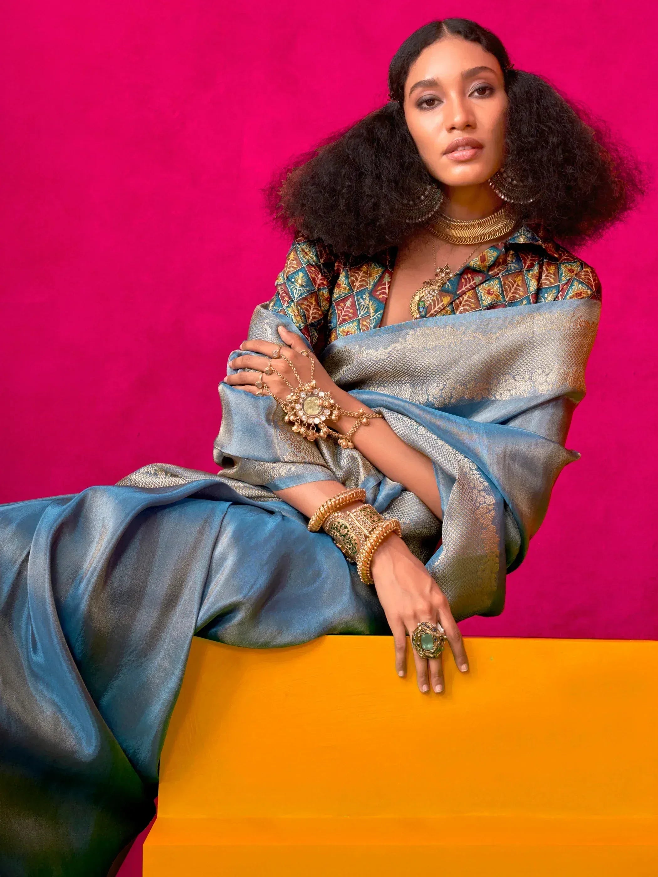 Elegant woman in blue silk saree with gold jewelry and printed blouse, styled for Indian ethnic wear.
