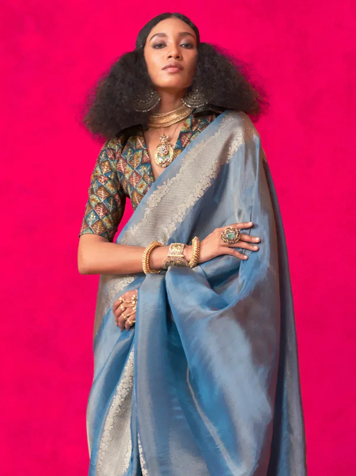 Blue silk saree with silver border, patterned blouse, and gold jewelry for ethnic wear