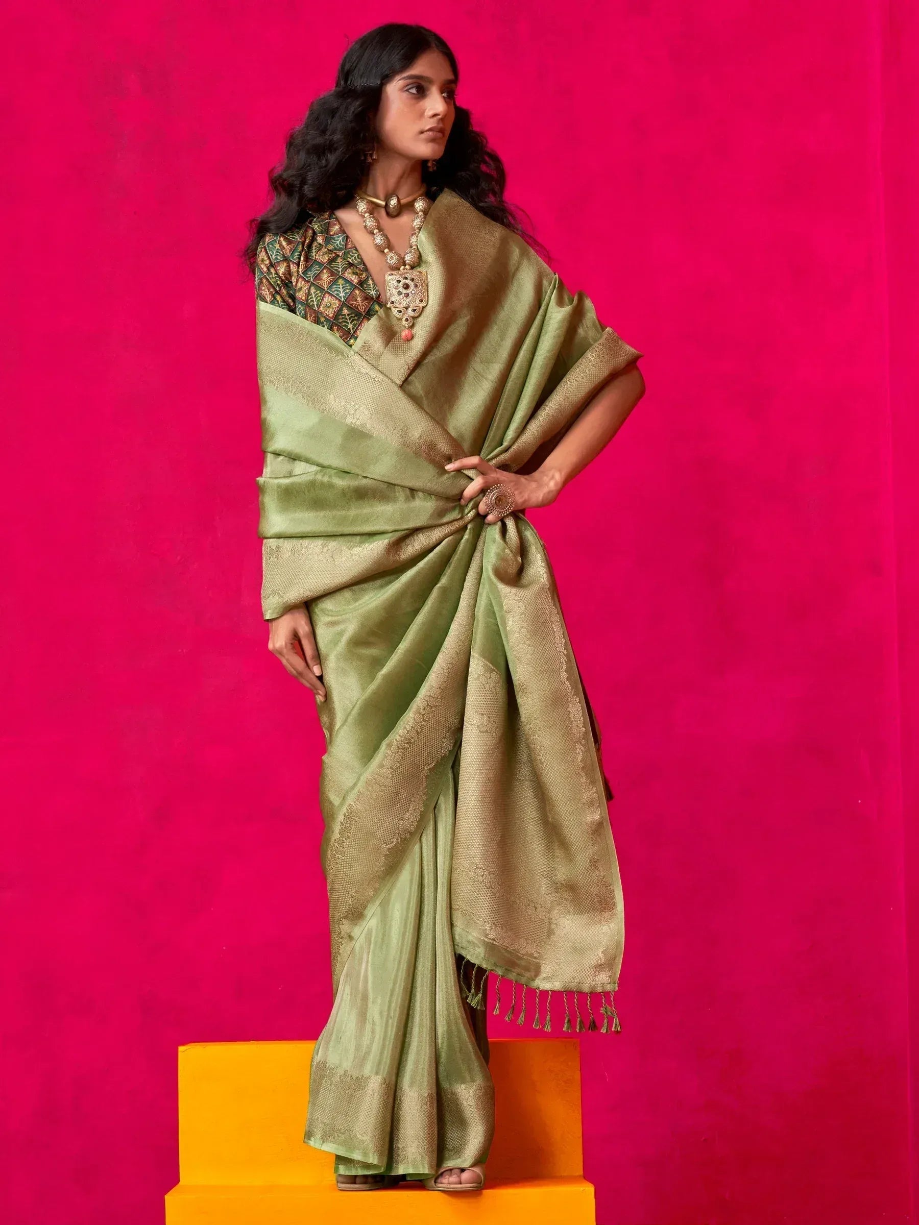 Elegant green saree with golden border and intricate blouse design, styled with traditional jewelry