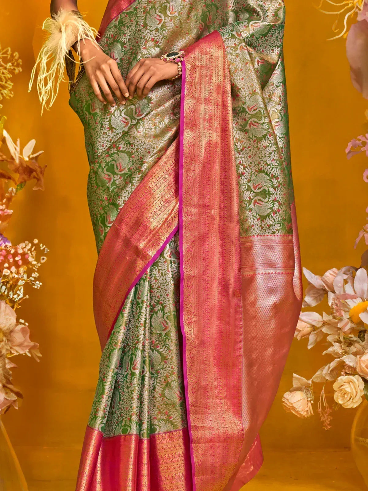Green and pink designer saree with floral motifs and golden border, perfect for ethnic occasions.