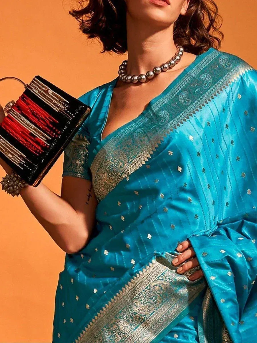 Turquoise designer saree with gold paisley border, paired with statement necklace and embellished clutch