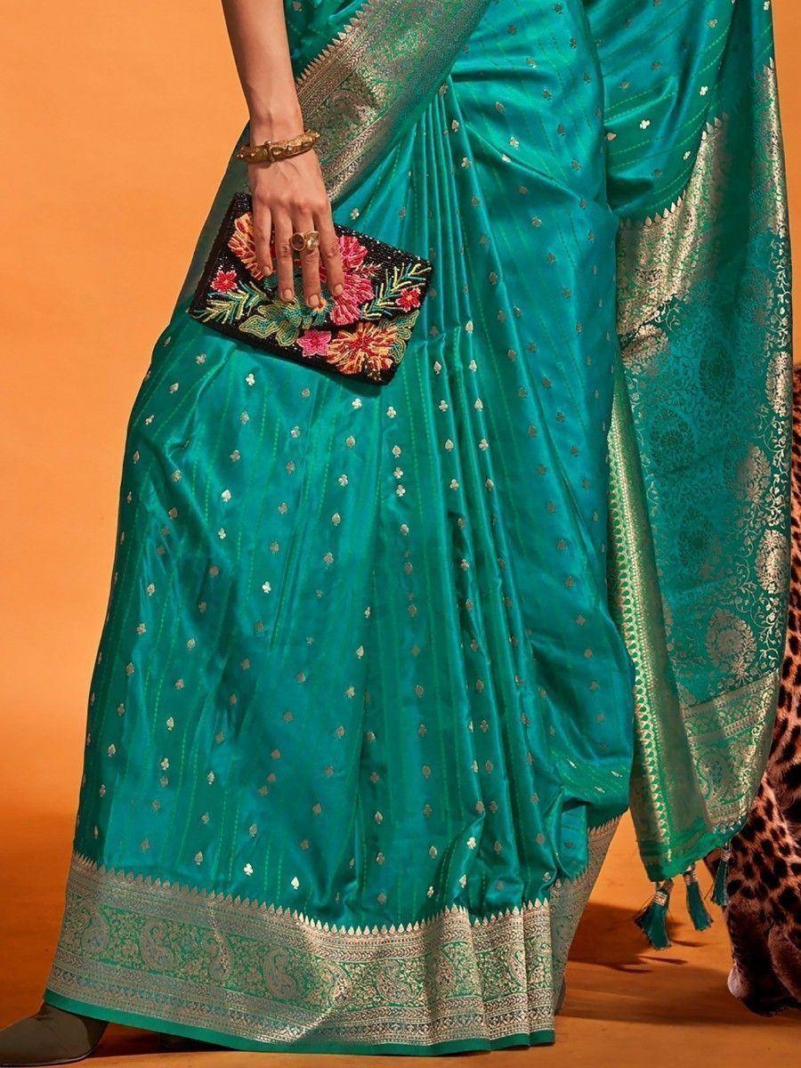 Teal silk saree with gold zari border and floral clutch, perfect for Indian ethnic occasions