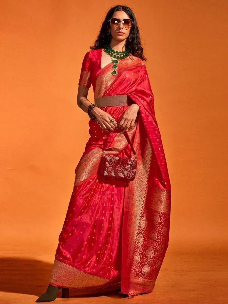 Red designer saree with gold border, green jewelry, and matching clutch for ethnic wear