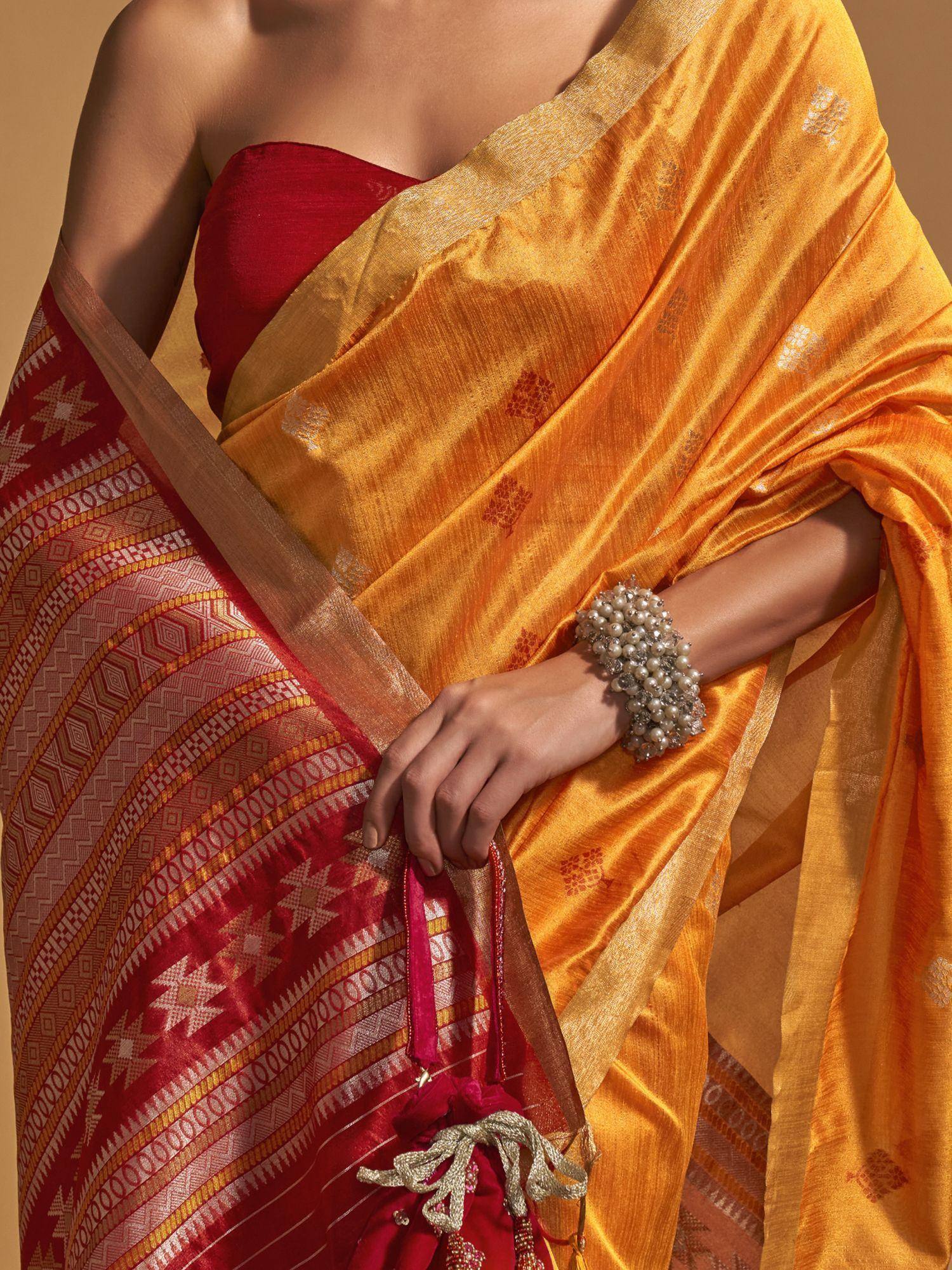 Golden saree with red blouse and intricate geometric border, styled with pearl bracelet for ethnic wear