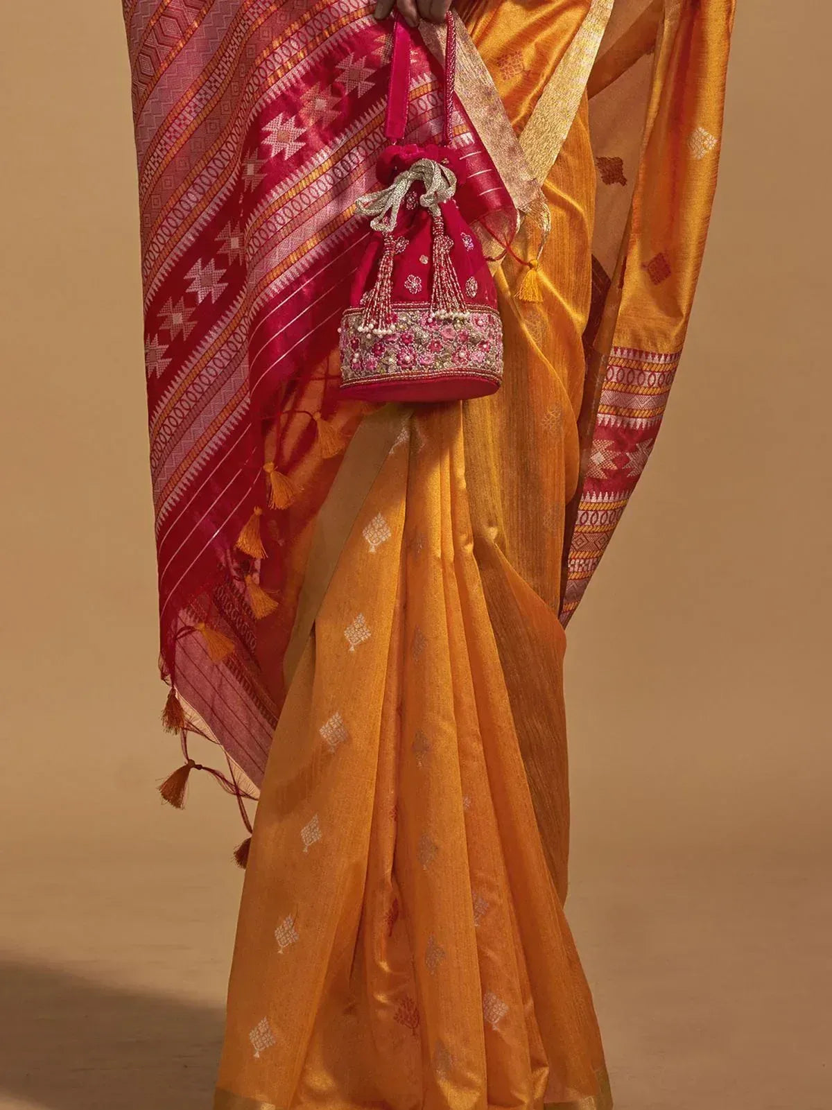Golden saree with red border, ethnic embroidery, and matching potli bag for Indian festive wear