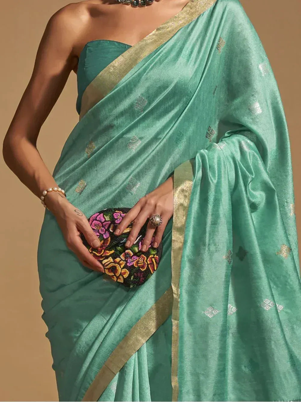 Teal silk saree with gold border and floral clutch, elegant Indian ethnic wear