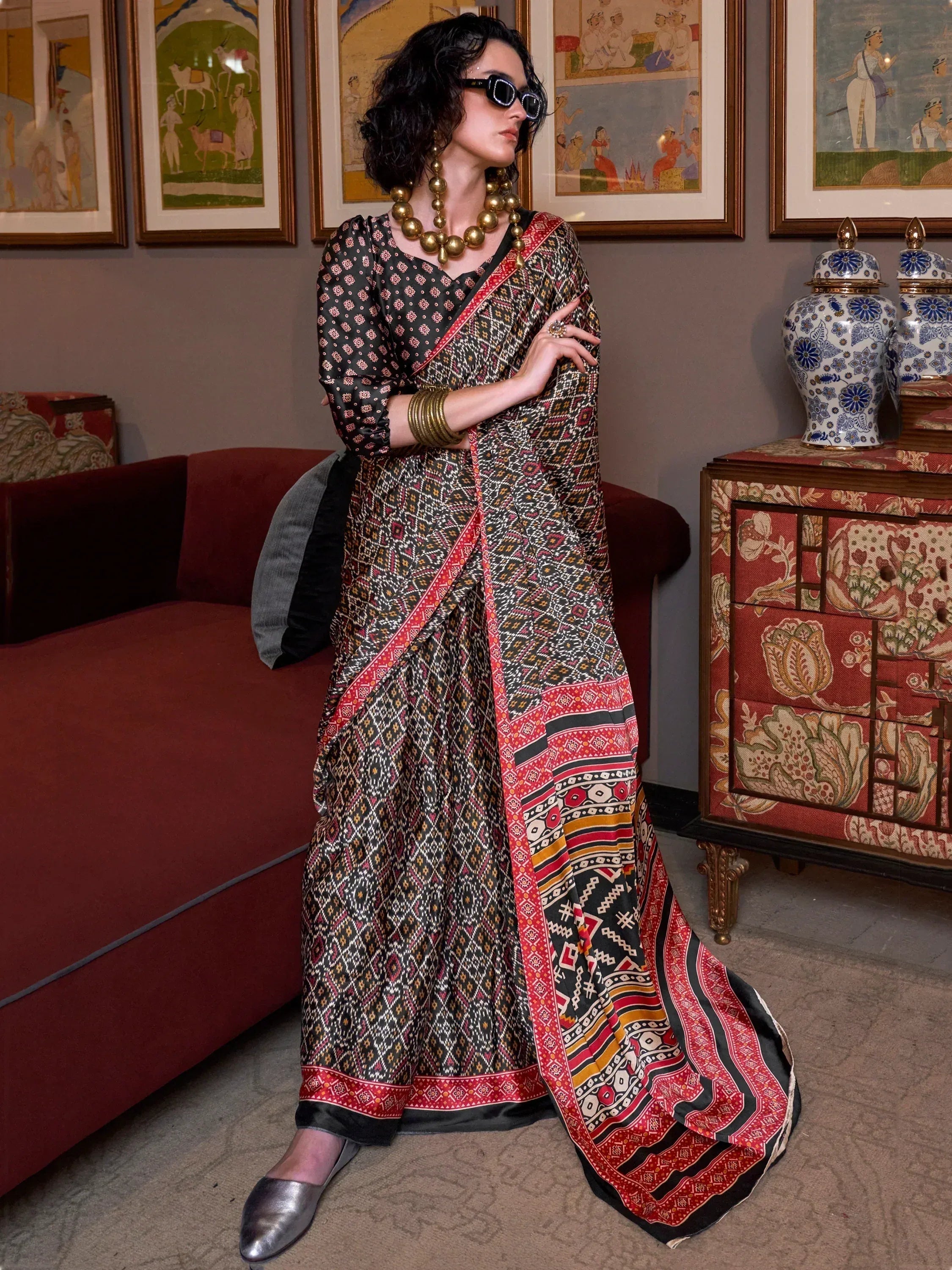 Woman in black and red printed ethnic saree with gold jewelry, styled for modern Indian wear