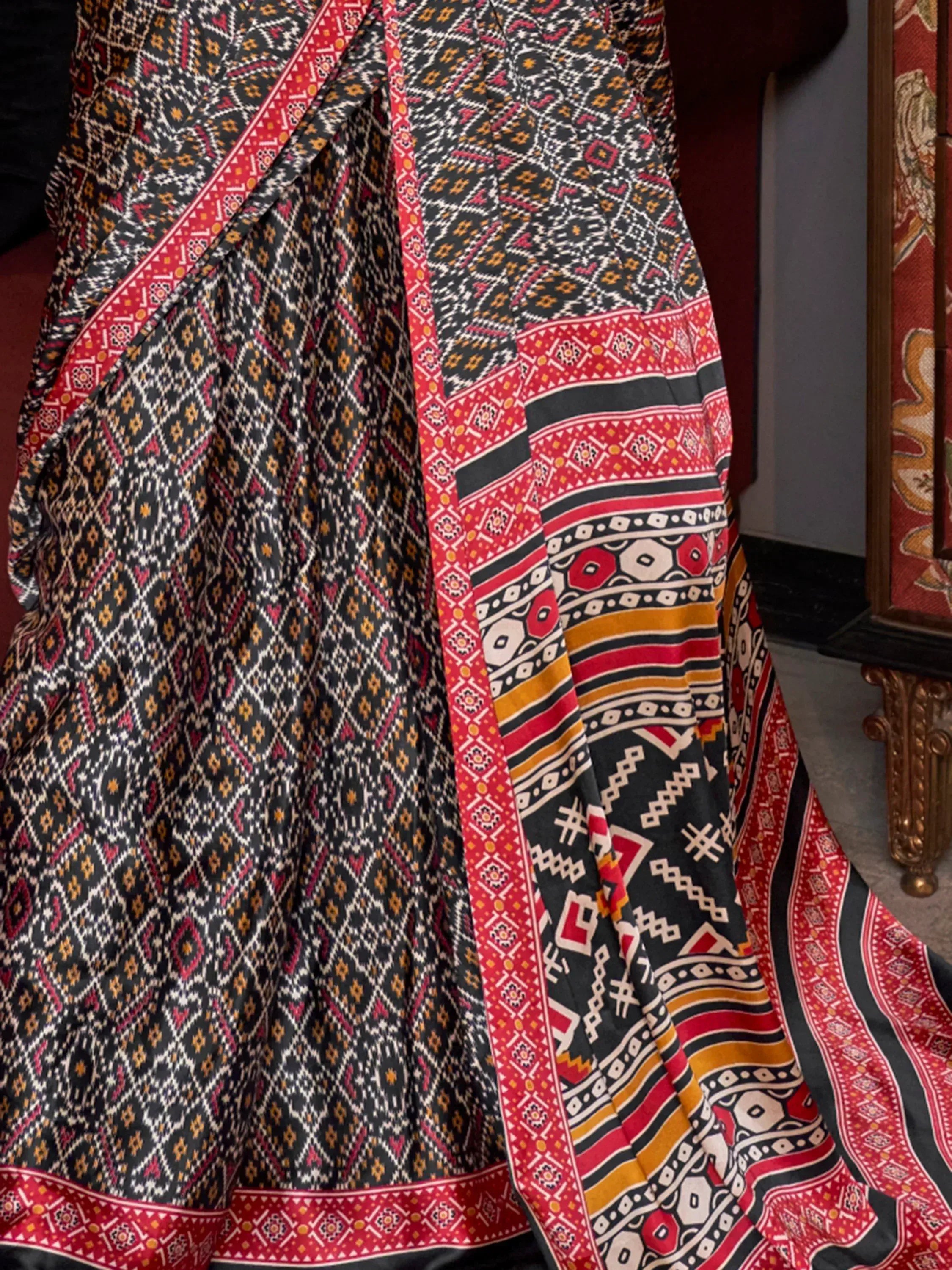 Black and red ethnic saree with geometric patterns and vibrant border designs