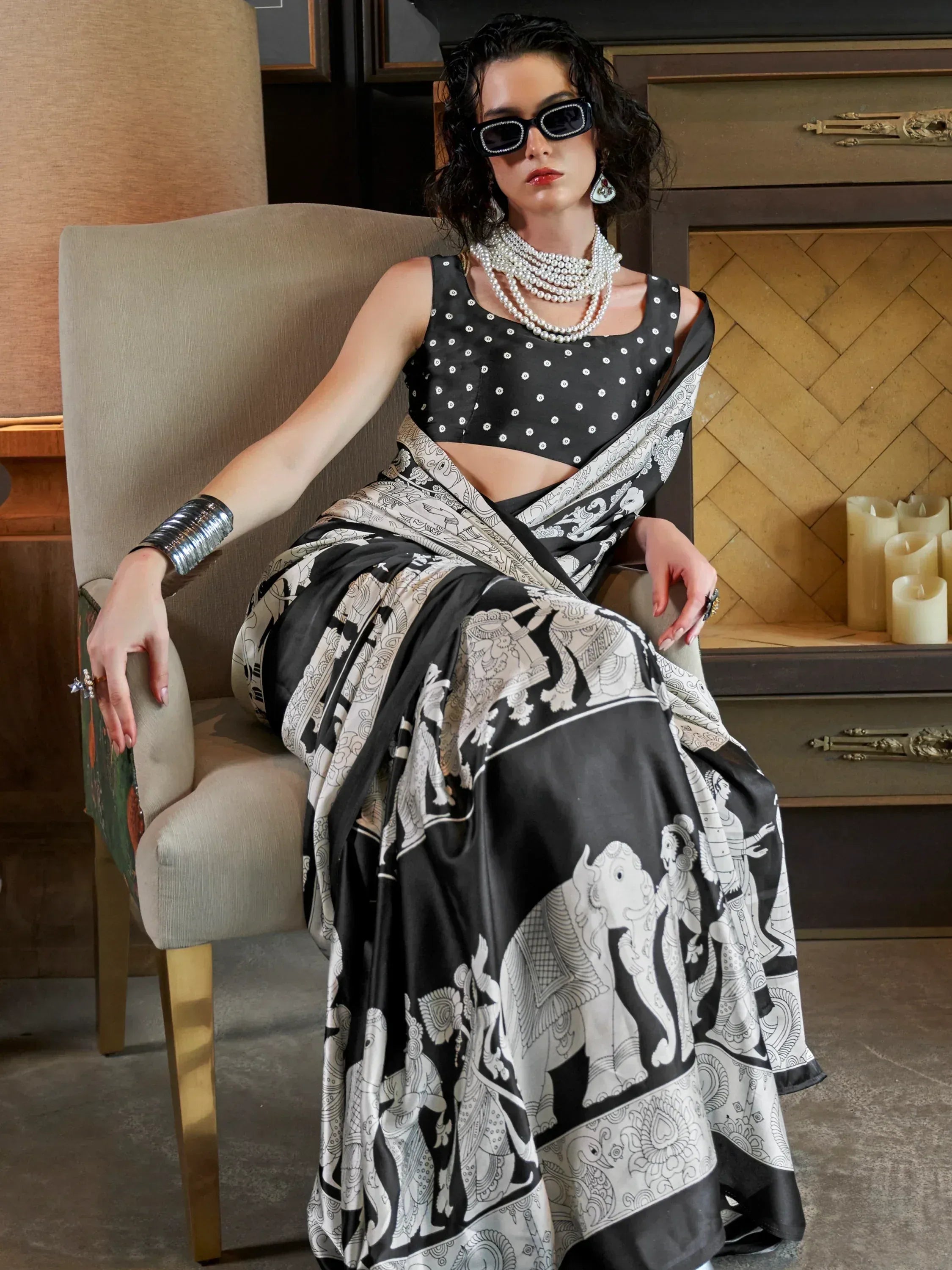 Woman in black and white printed saree with polka dot blouse, styled with pearls and sunglasses