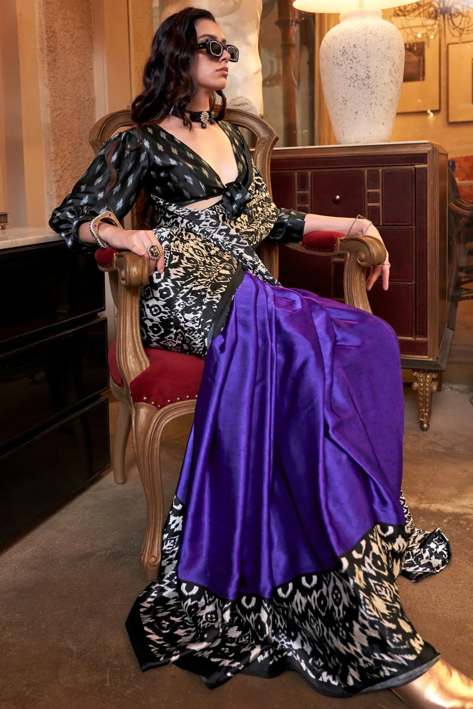 Woman in black and white ikat print ethnic gown with purple satin drape, styled with sunglasses and choker