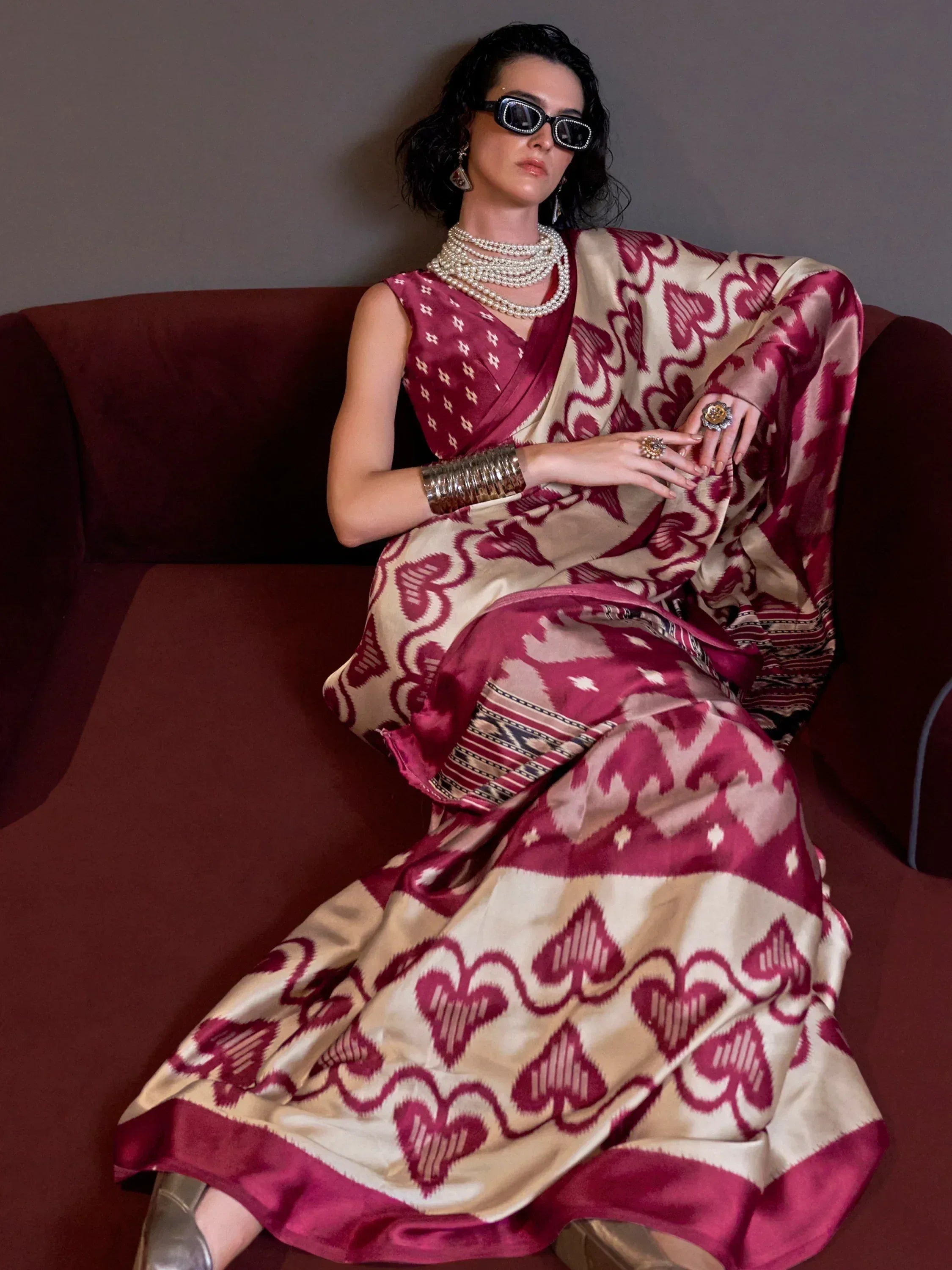 Woman in maroon and cream ikat saree with heart pattern, styled with pearl necklace and sunglasses