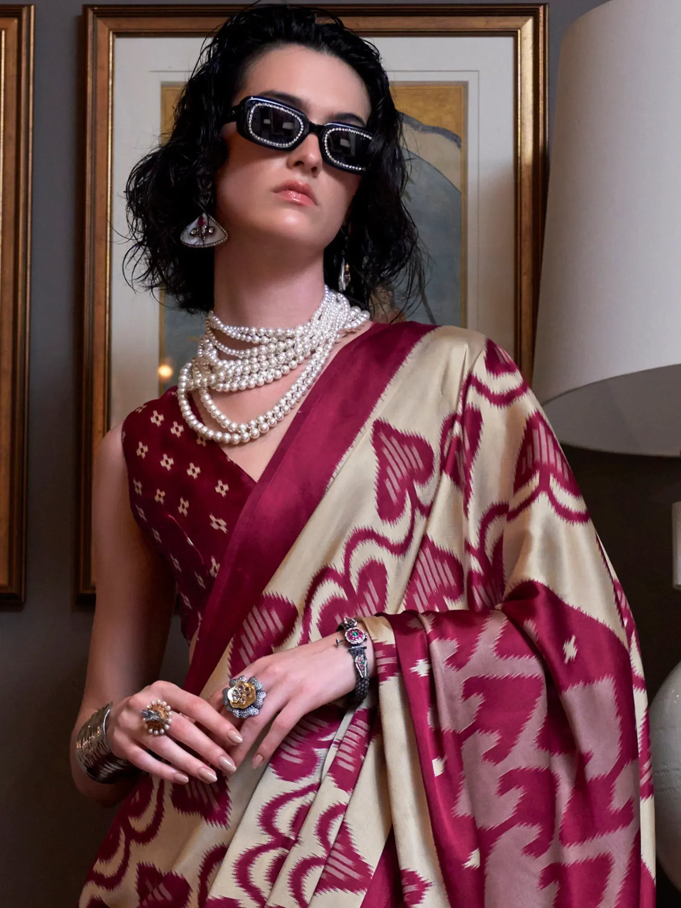 Woman in maroon and cream ikat saree with pearl jewelry and sunglasses, styled for ethnic fashion