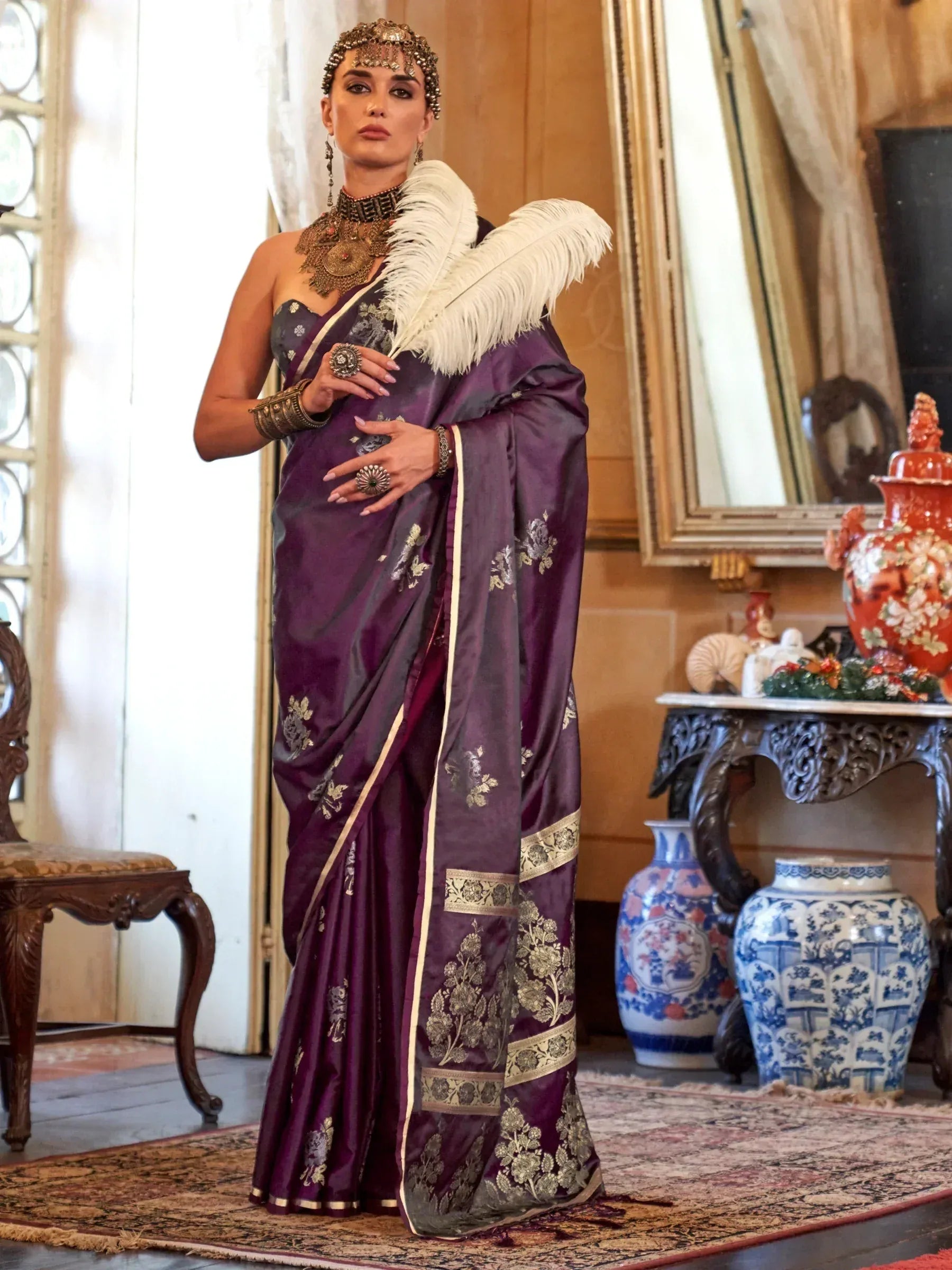 Elegant purple saree with gold floral embroidery, feather accent, and traditional Indian jewelry for festive occasions.