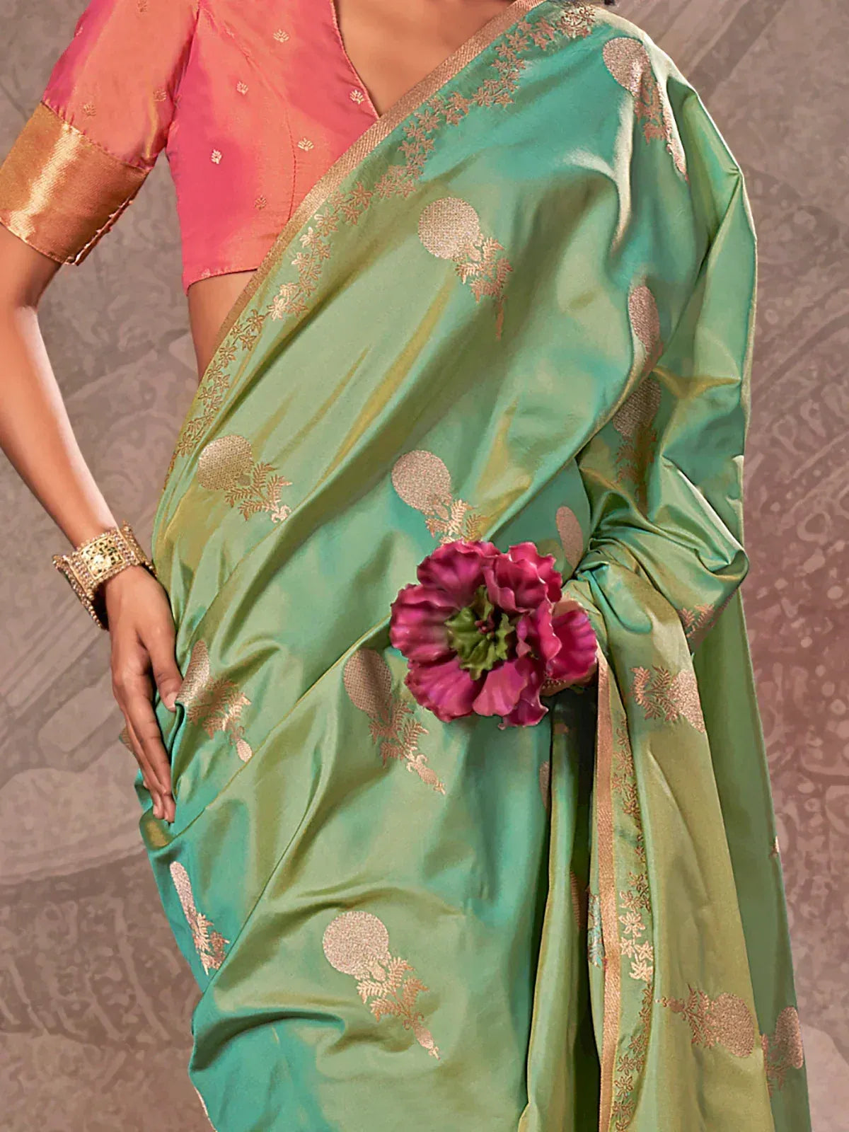 Green silk saree with gold floral motifs, pink blouse, and floral accessory for Indian ethnic wear