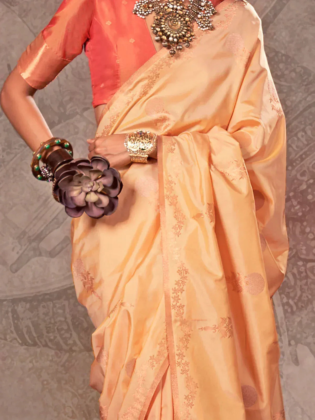 Peach silk saree with gold embroidery, paired with coral blouse and traditional jewelry for Indian ethnic wear