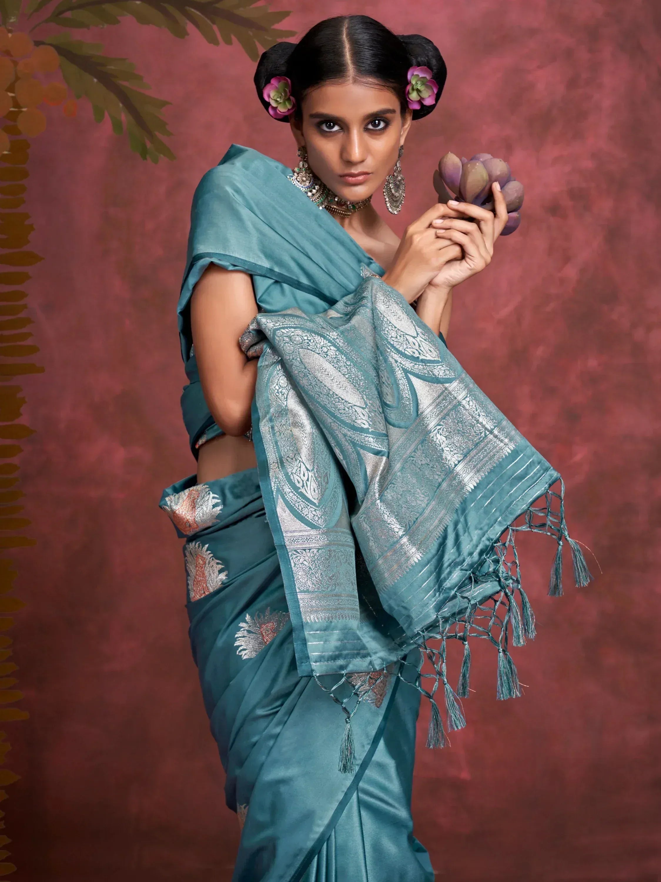 Teal designer saree with silver zari work and tassels, styled with floral hair accessories