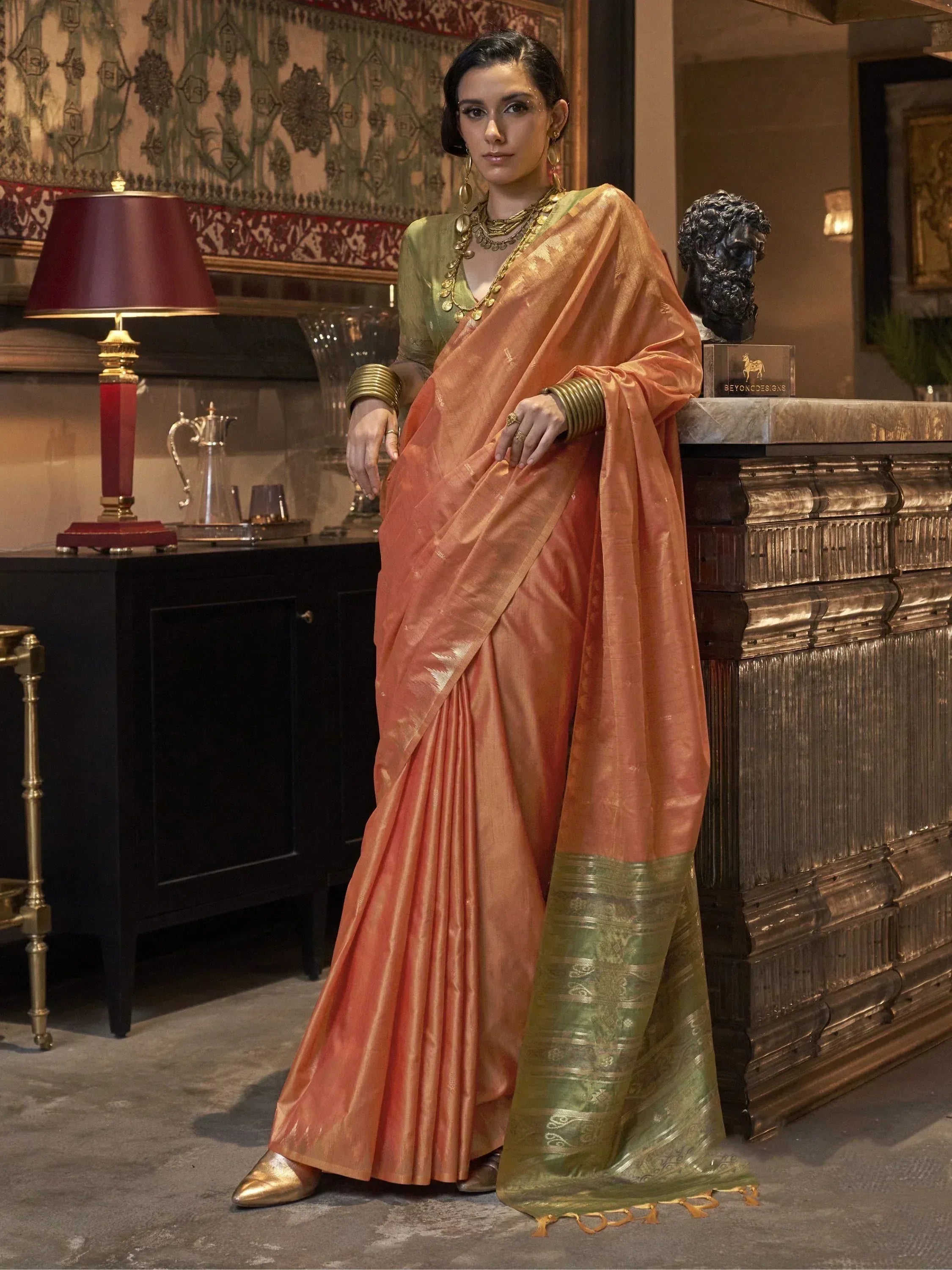 Woman in elegant peach and green silk saree with gold jewelry, styled for Indian ethnic wear
