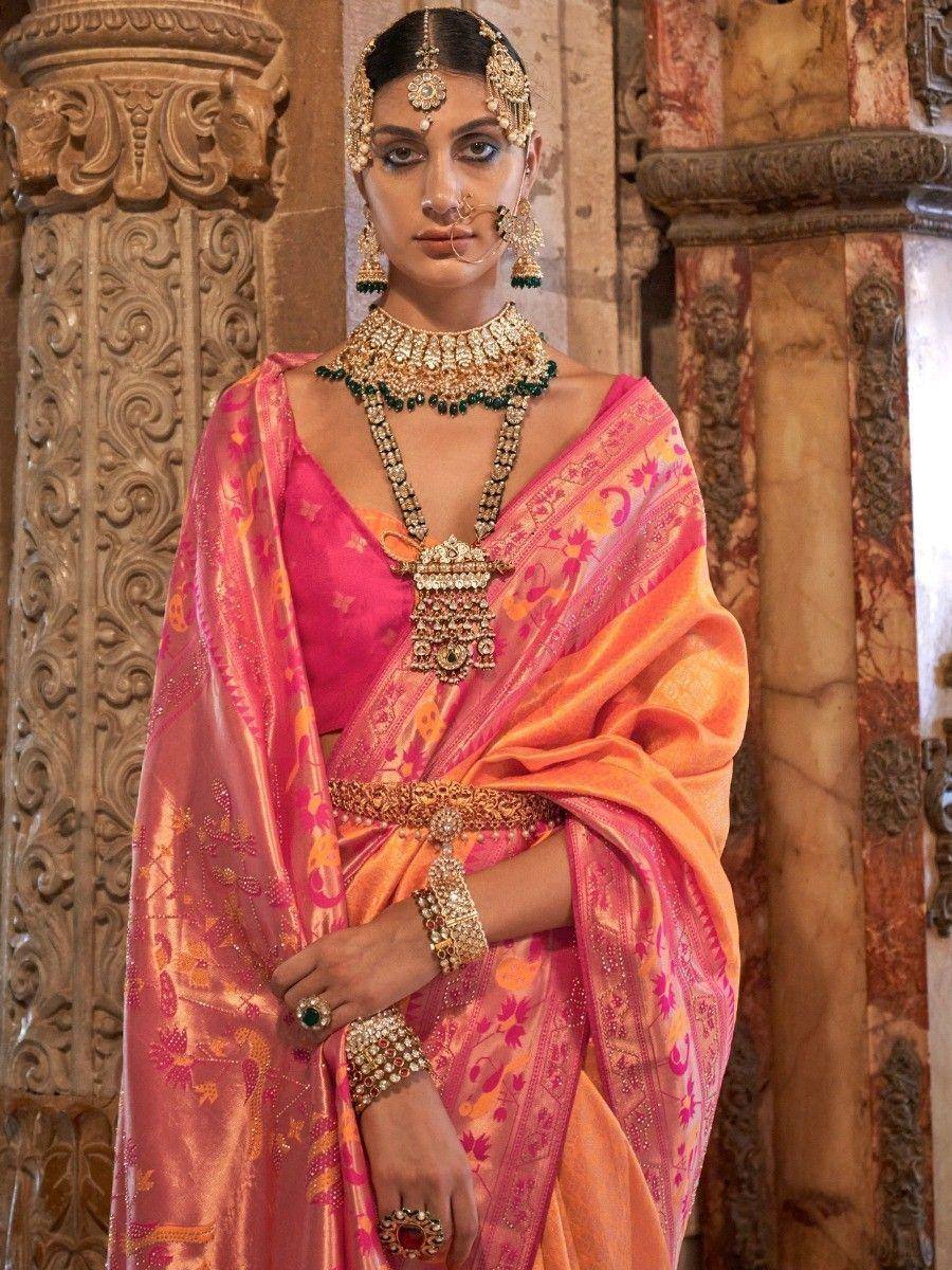 Woman in vibrant pink and orange designer saree with heavy gold jewelry, traditional Indian ethnic wear
