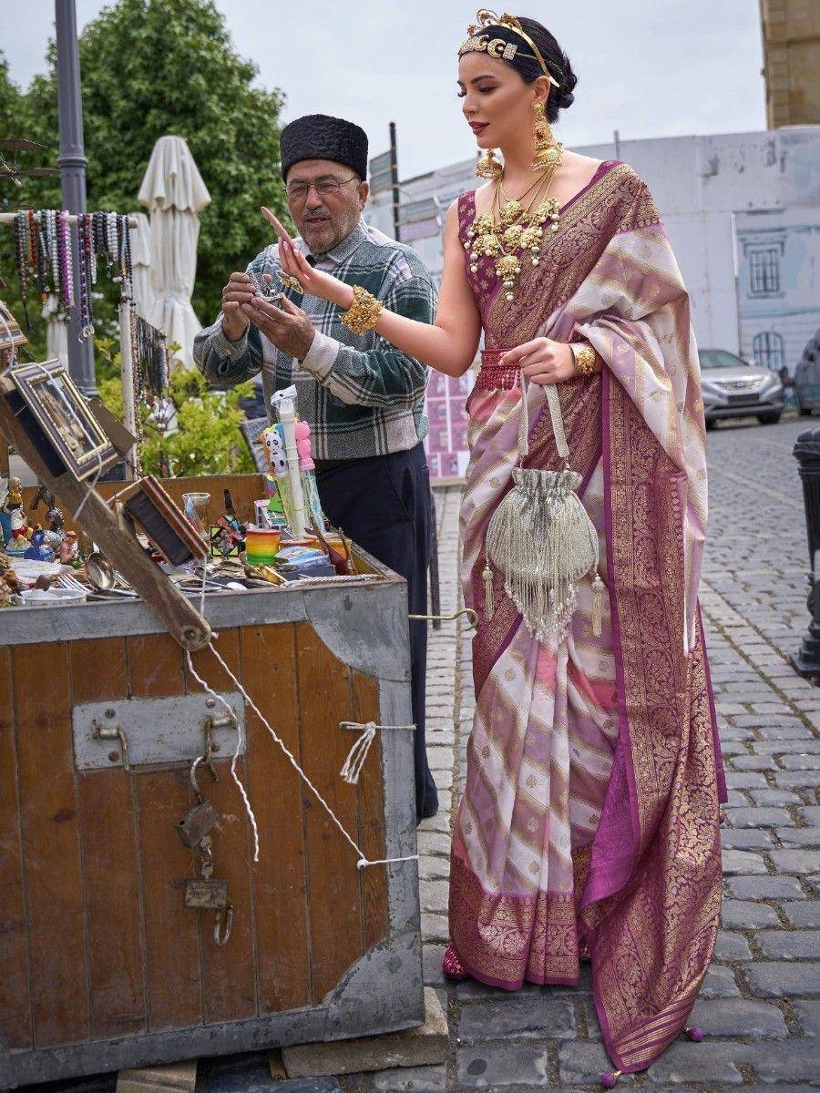 Woman in elegant purple and gold ethnic saree with traditional jewelry at outdoor market stall
