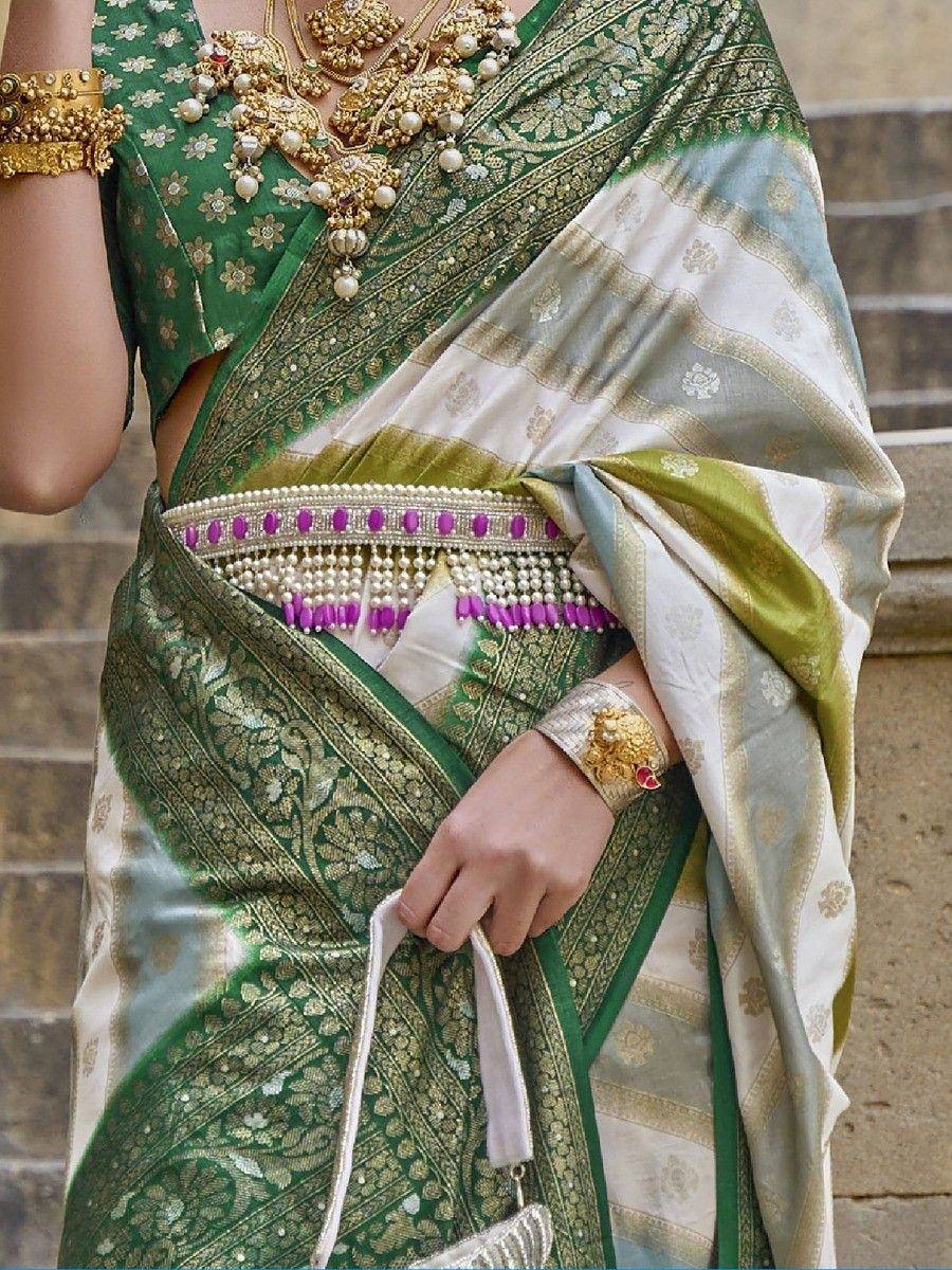 Green and white designer saree with gold embroidery, pearl jewelry, and purple beaded belt for ethnic wear