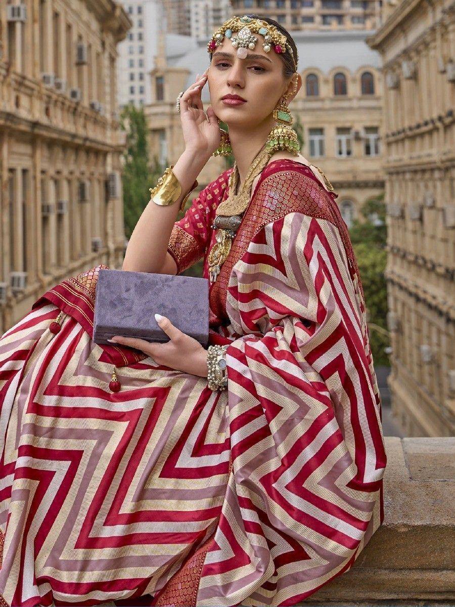 Woman in red and gold geometric patterned lehenga choli with traditional jewelry, holding clutch