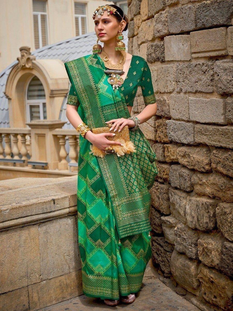 Elegant green ethnic saree with gold embroidery, paired with traditional jewelry and clutch, perfect for festive occasions.