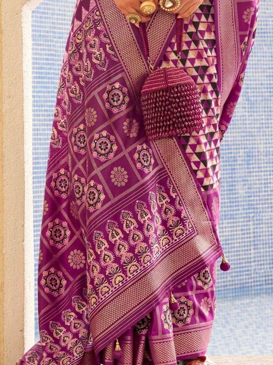 Purple ethnic saree with intricate floral and geometric patterns, paired with beaded clutch and gold jewelry